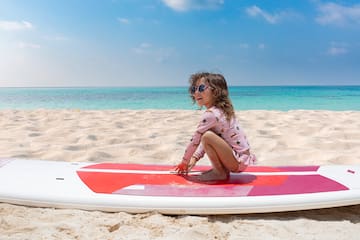 a girl sitting on a surfboard on a beach