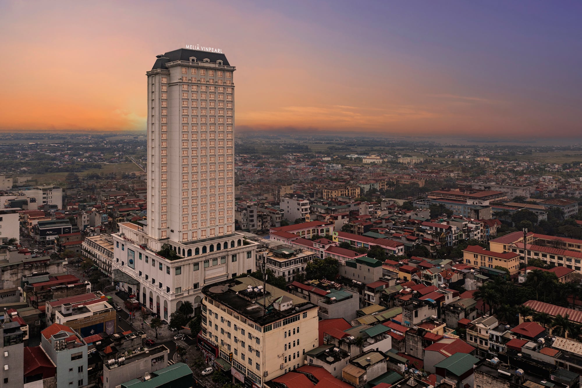 Meliã Vinpearl hotel skyscraper dominates city skyline at sunset.