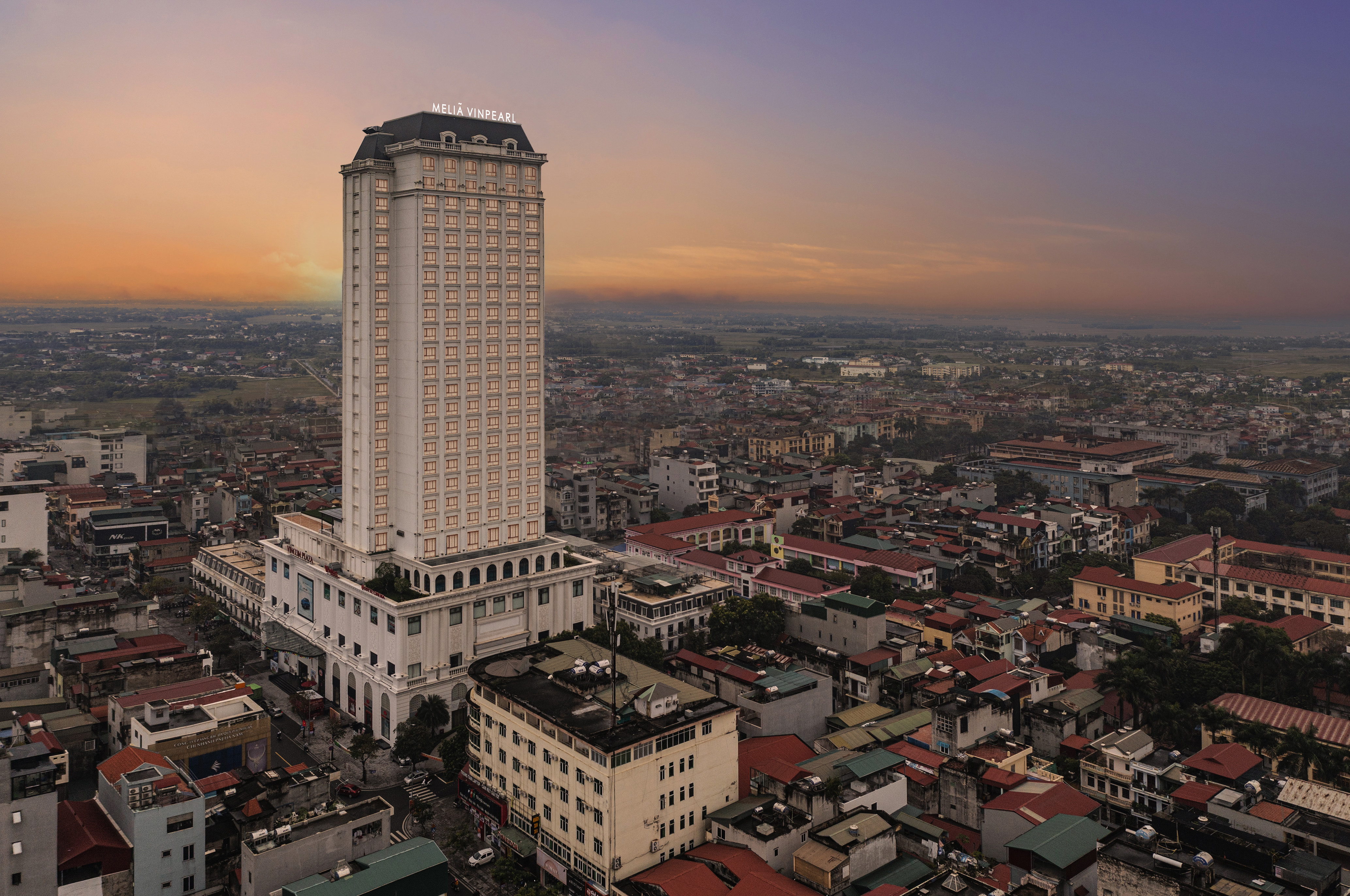 Meliã Vinpearl hotel skyscraper dominates city skyline at sunset.