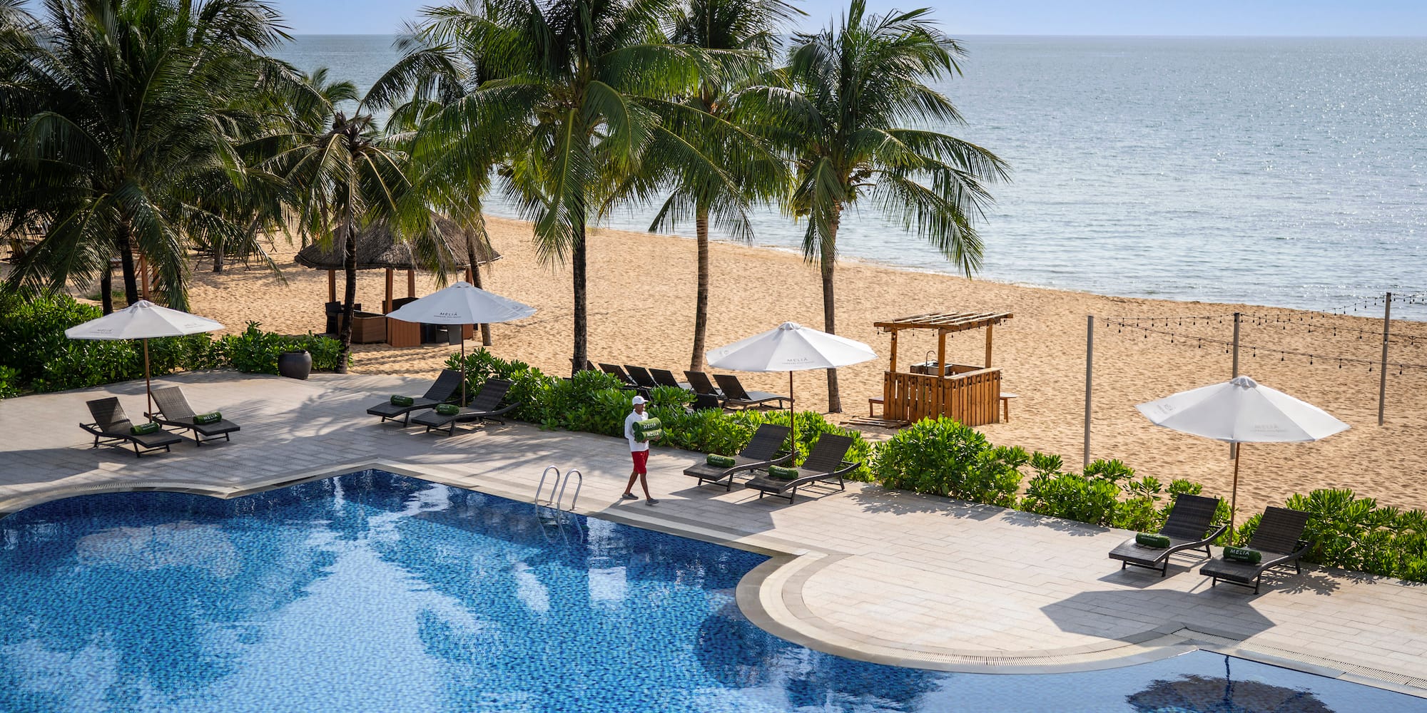 a pool with palm trees and a person walking on it