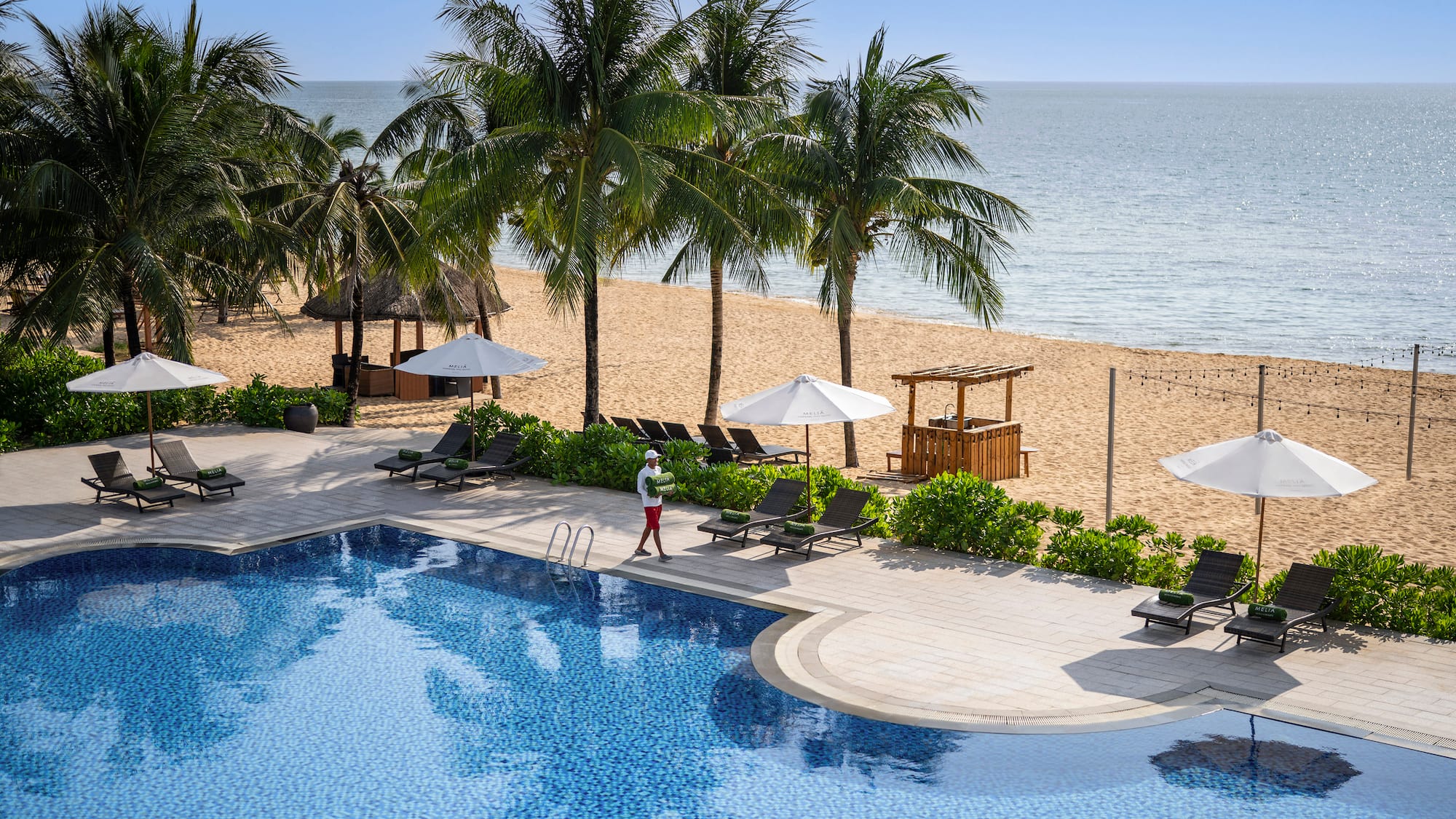 a pool with palm trees and a person walking on it