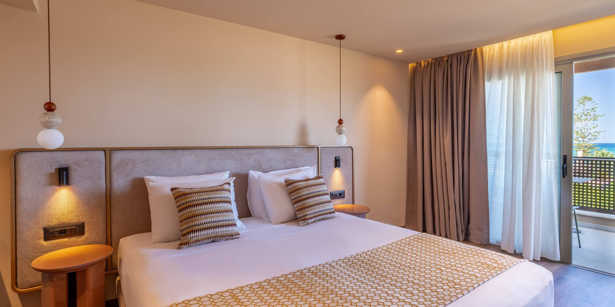 Modern hotel room with bed, patterned runner, and balcony ocean view.