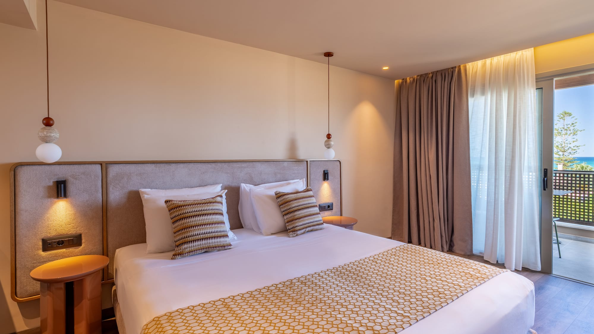 Modern hotel room with bed, patterned runner, and balcony ocean view.