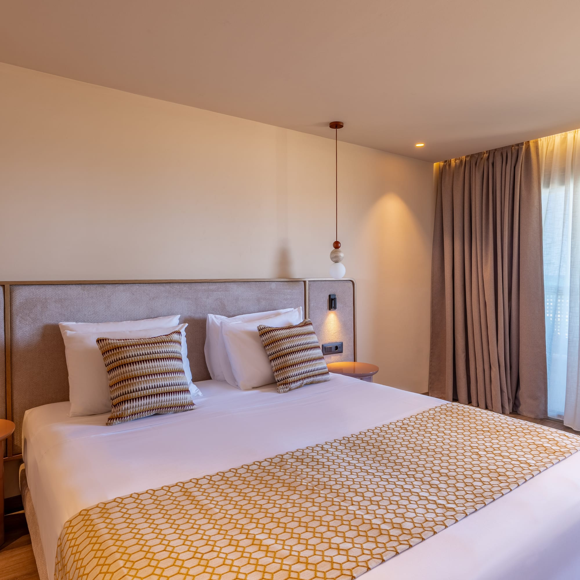 Modern hotel room with bed, patterned runner, and balcony ocean view.