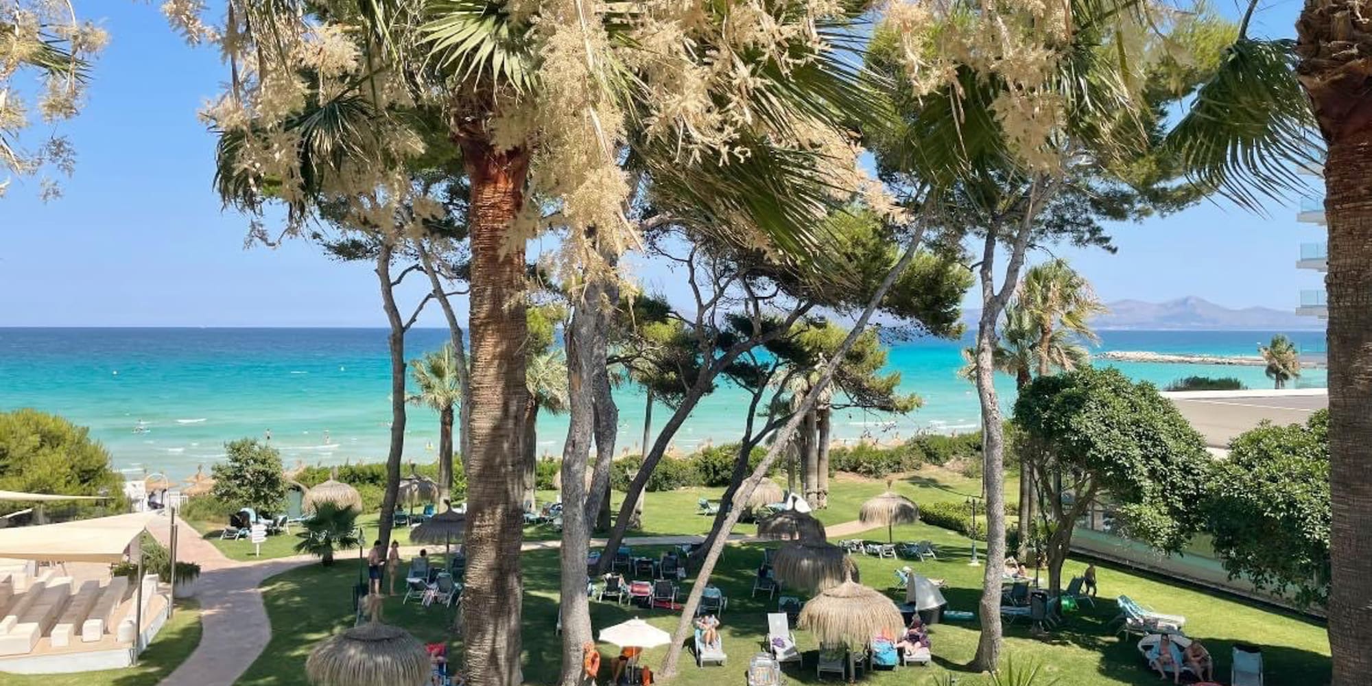 a pool with chairs and umbrellas by a beach