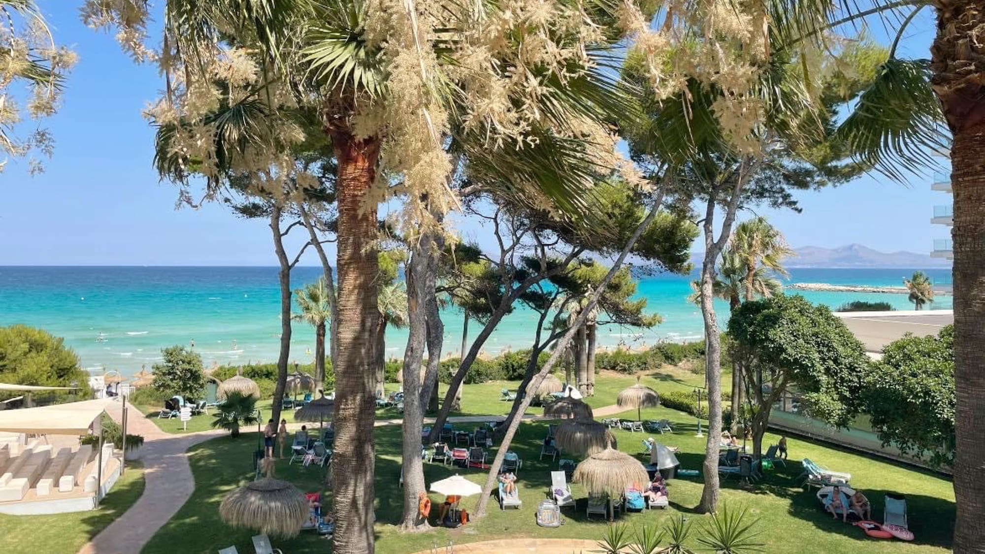 a pool with chairs and umbrellas by a beach