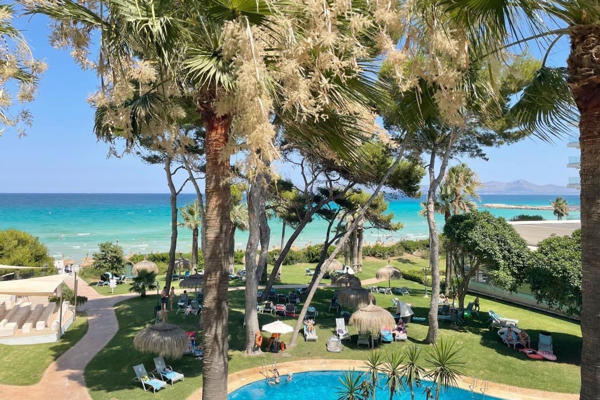 a pool with chairs and umbrellas by a beach