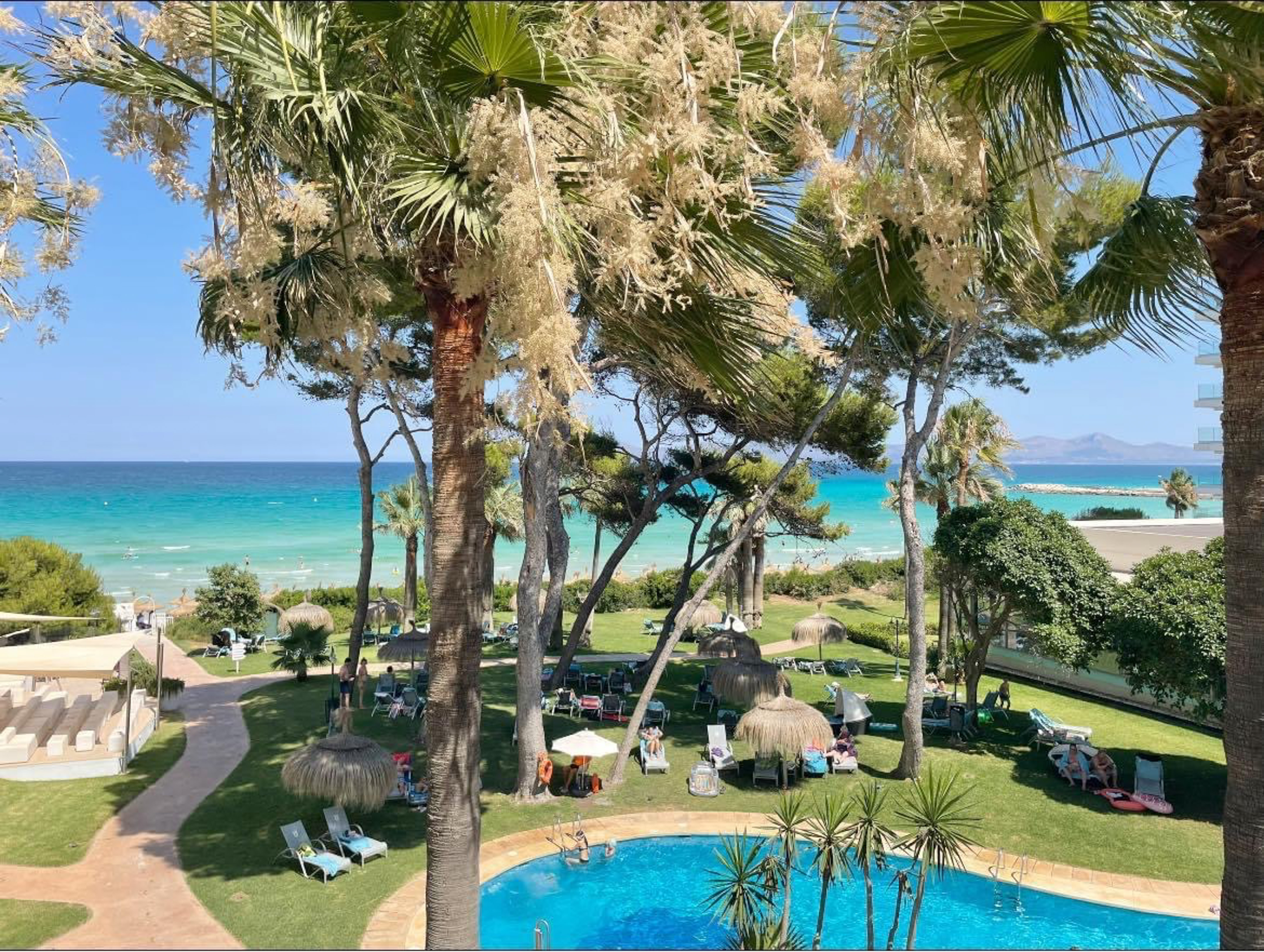 a pool with chairs and umbrellas by a beach