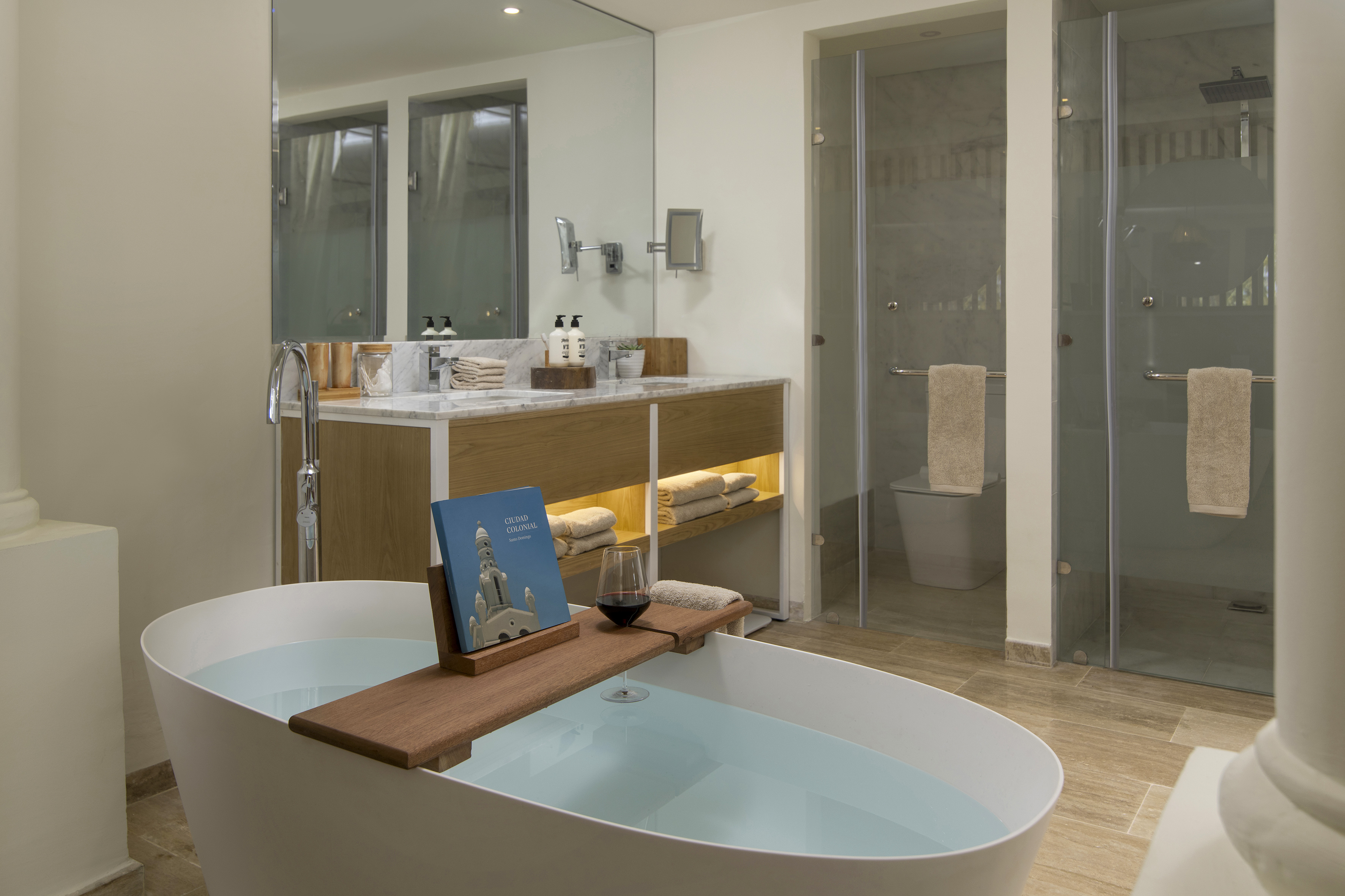 Luxury bathroom with freestanding tub, wine, book, modern vanity, showers.