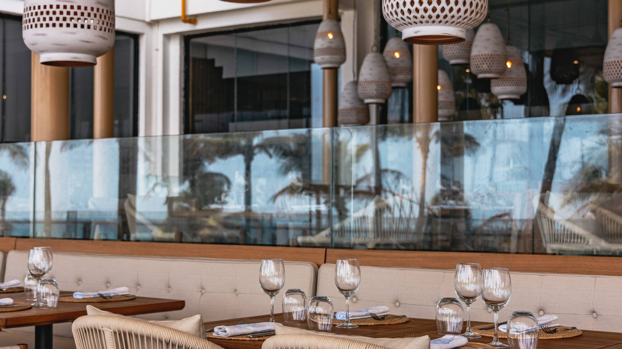 Resort dining patio with woven chairs, set tables, and decorative pendant lights.