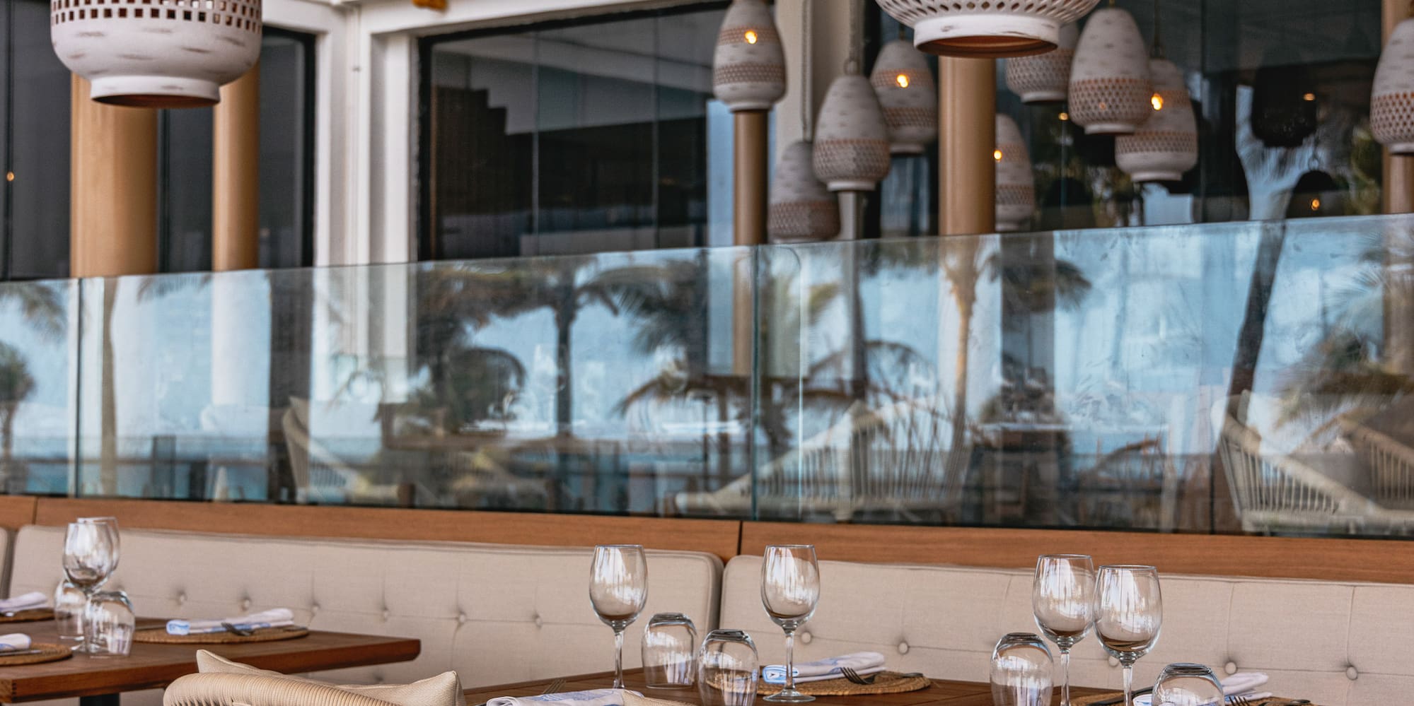 Resort dining patio with woven chairs, set tables, and decorative pendant lights.