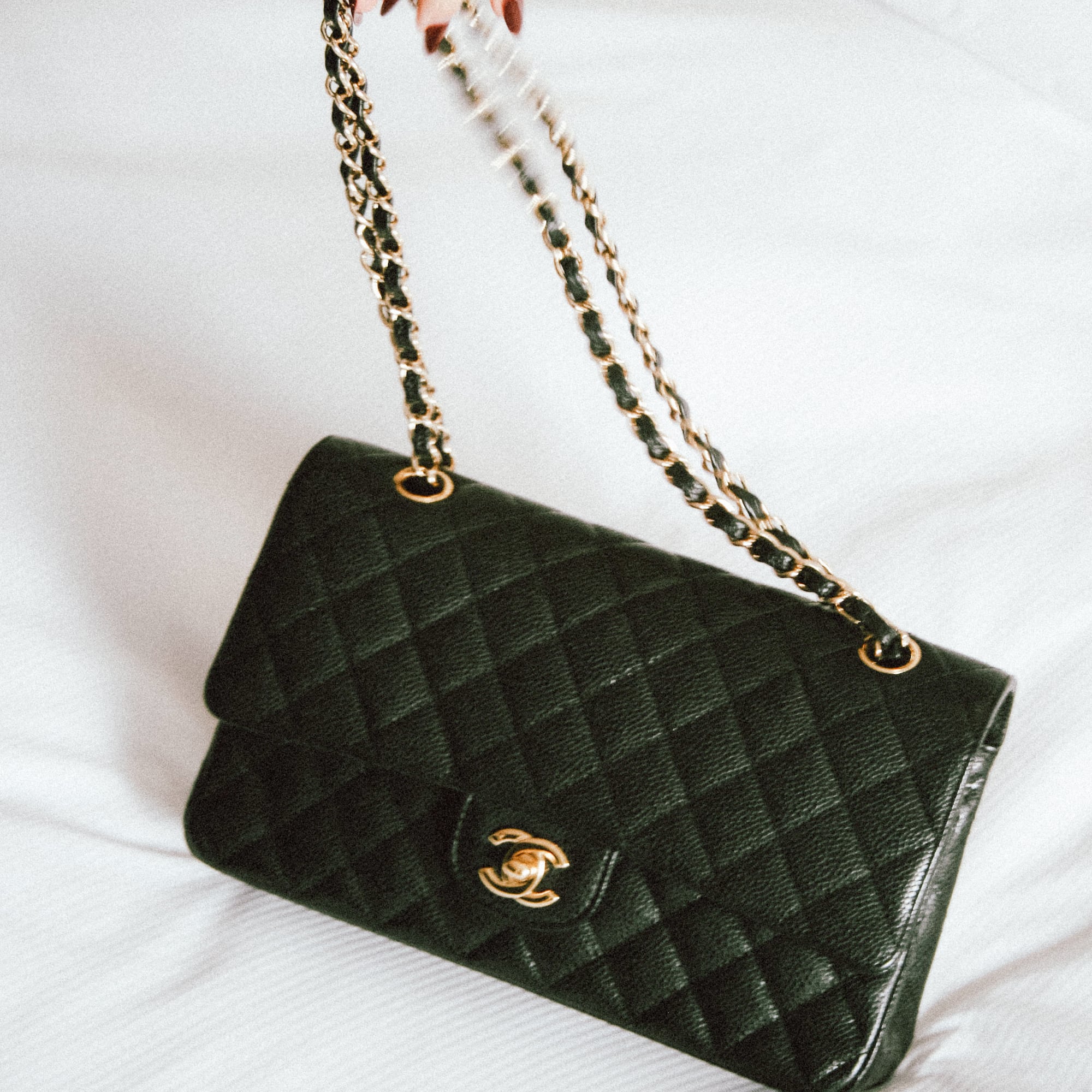 a hand holding a black purse