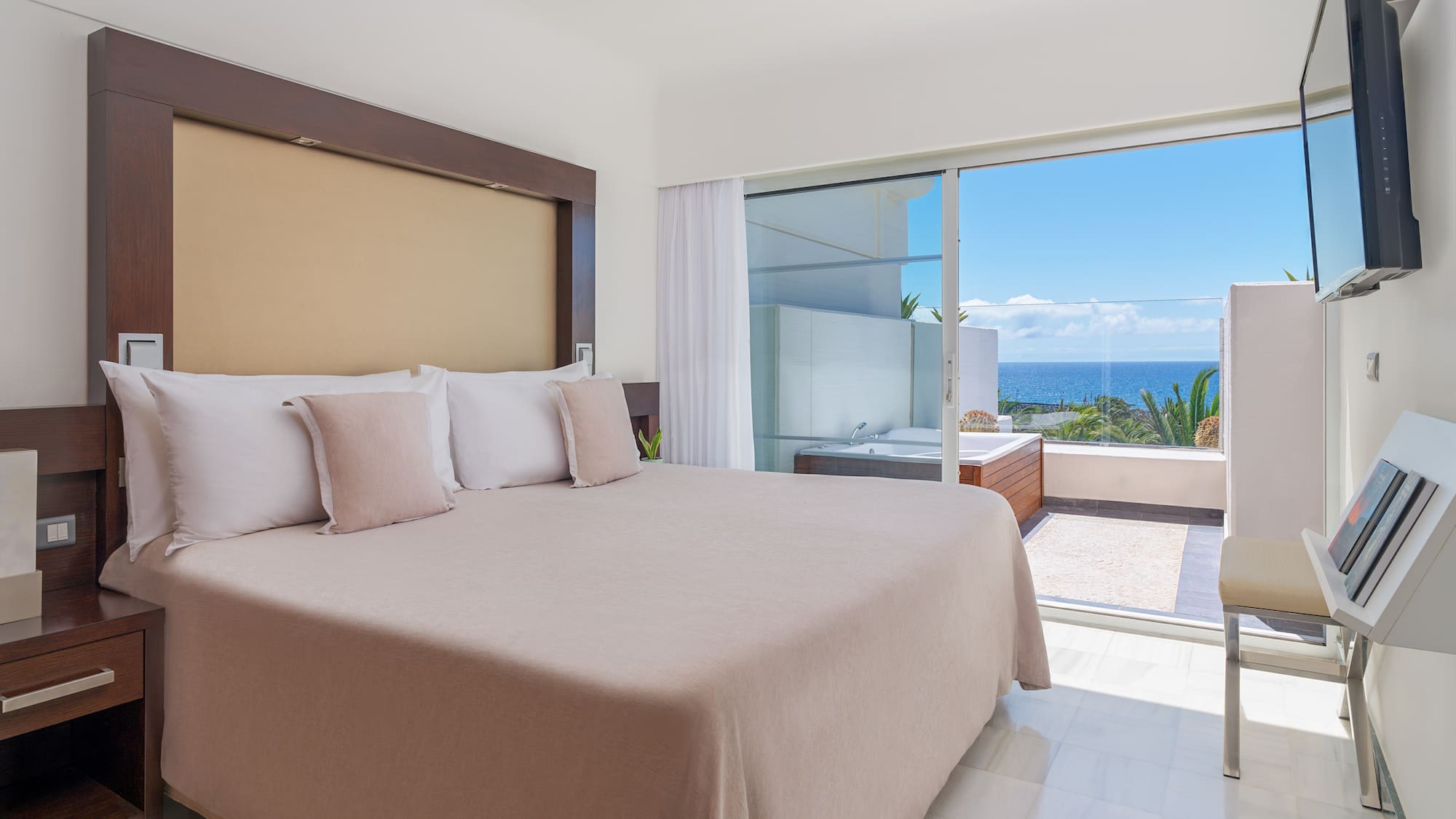 a bed with pillows in a room with a glass door