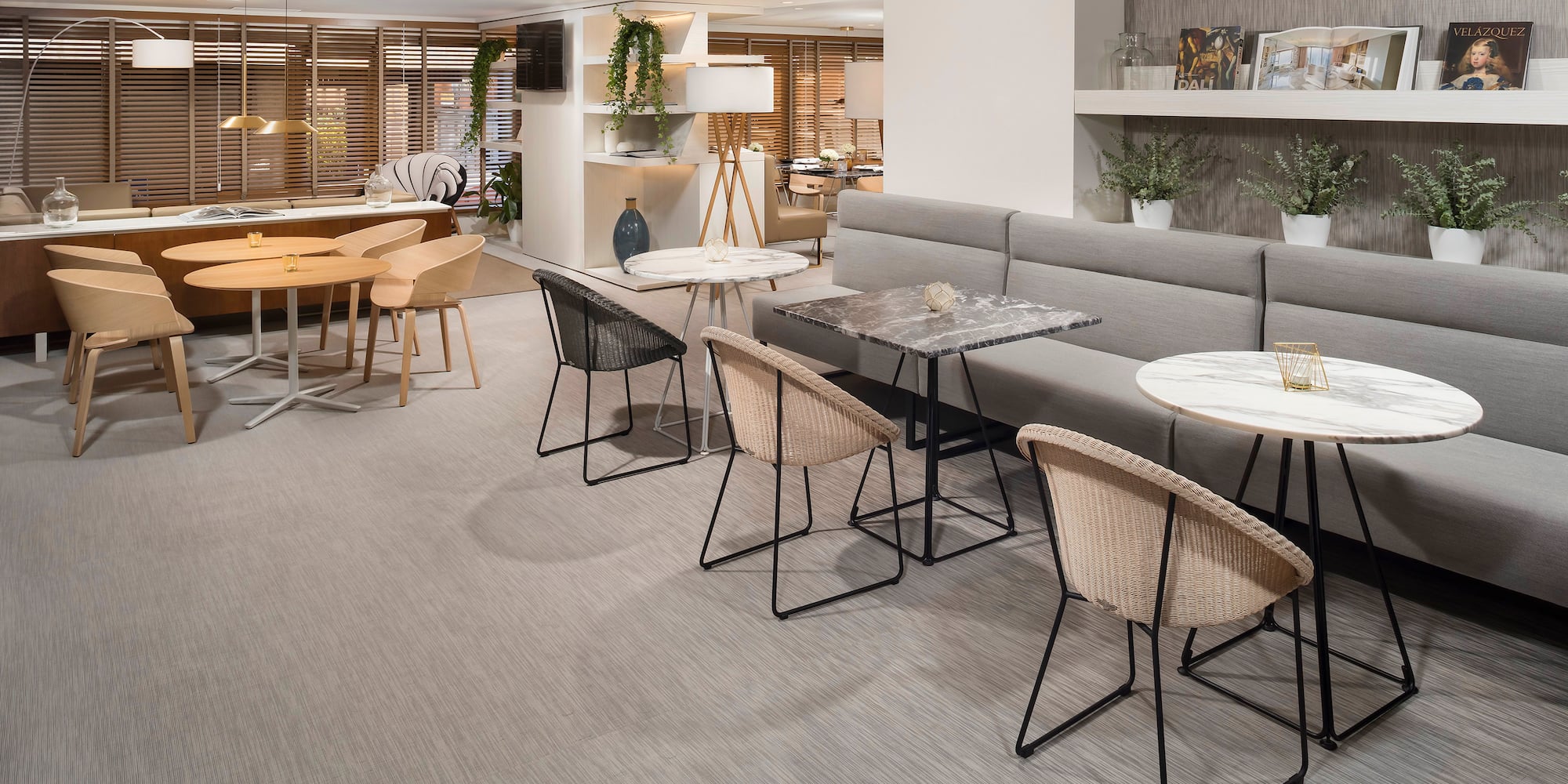 Modern lounge interior with varied seating, marble tables, and neutral decor.