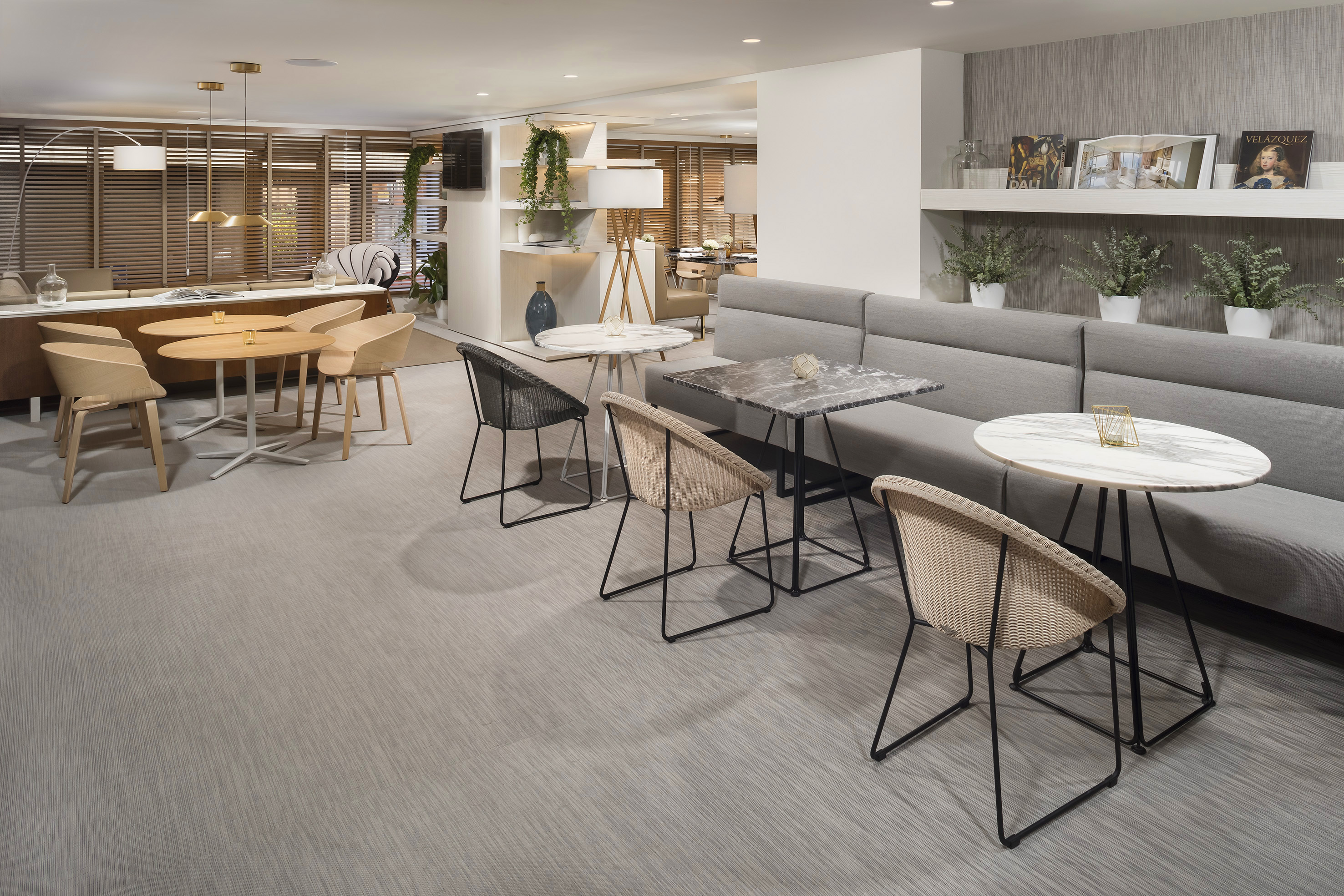 Modern lounge interior with varied seating, marble tables, and neutral decor.