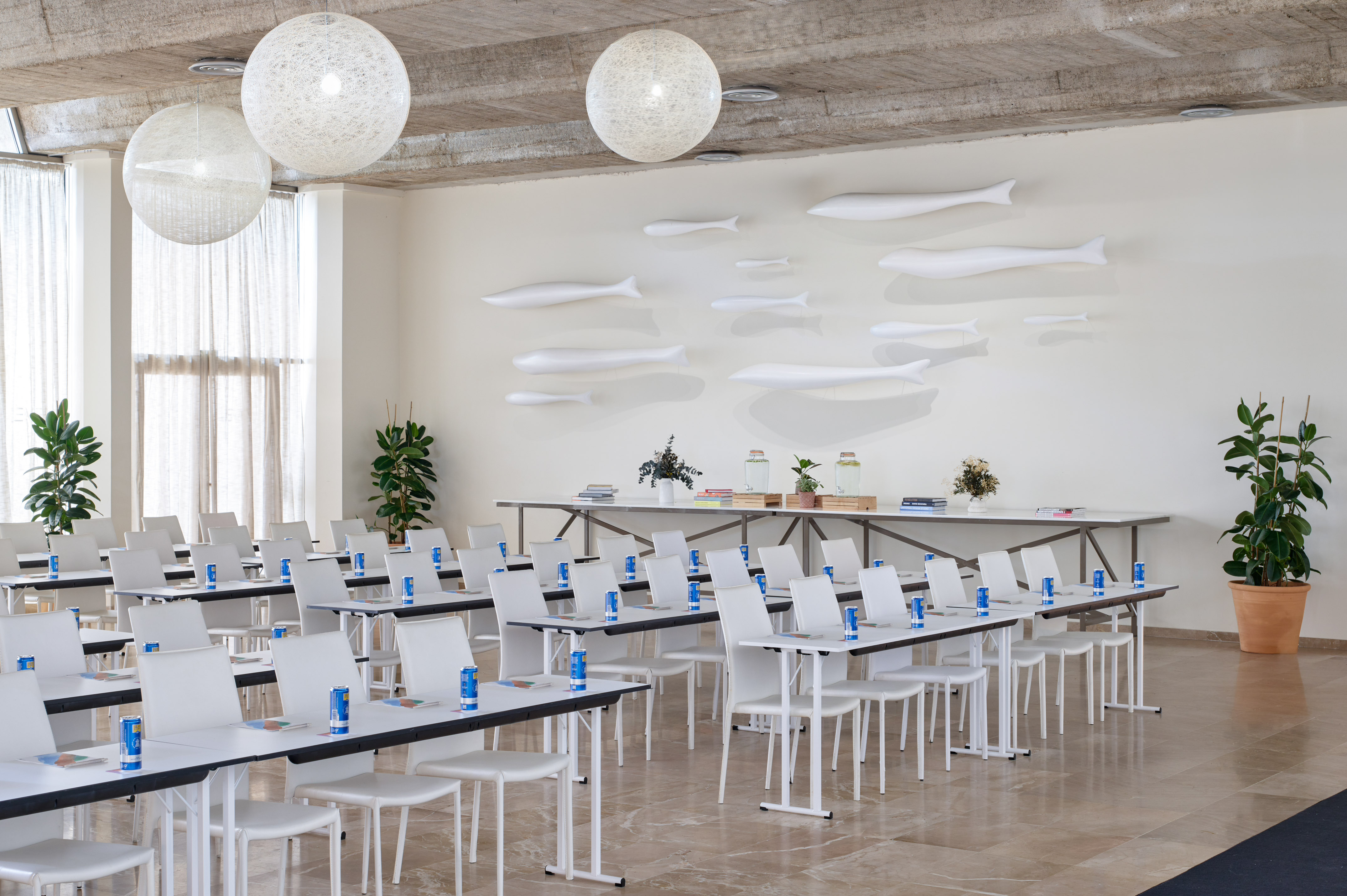Modern conference room with classroom seating, white tables, and fish wall art.