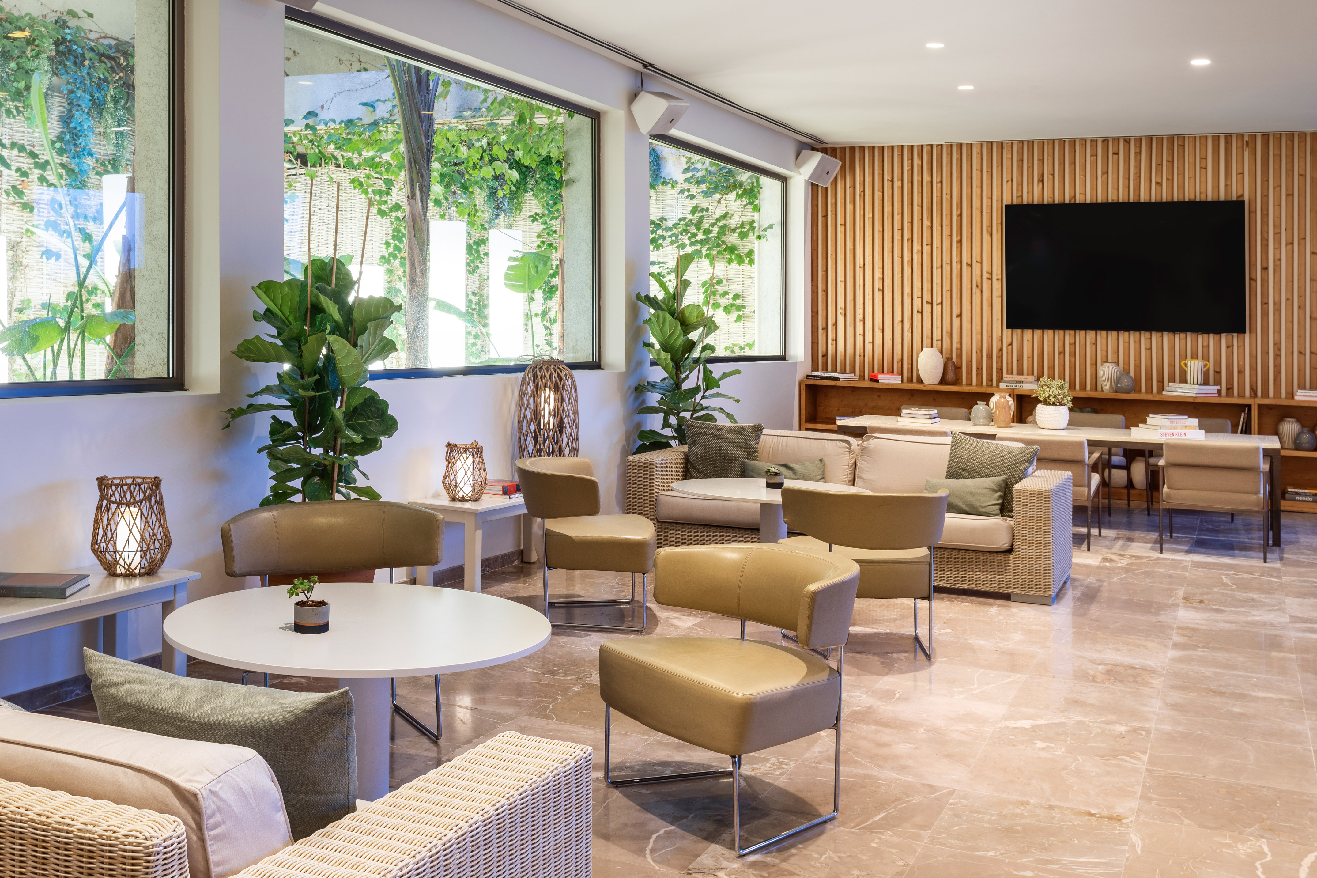 Stylish hotel lounge with tan sofas, large windows, and slatted wood wall.