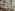 Elegant tropical restaurant interior with wooden tables, greenery, and classical mural.