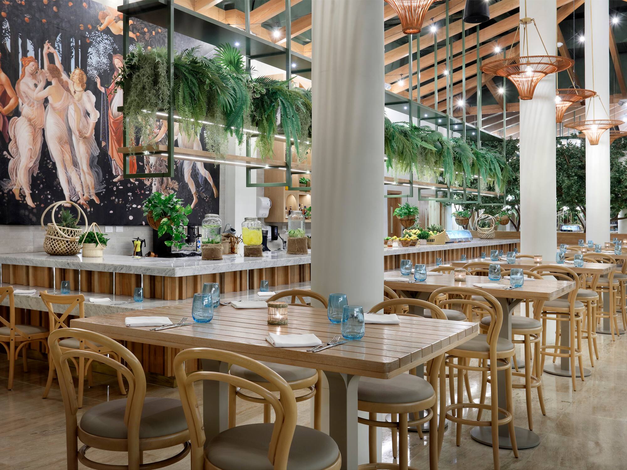 Elegant tropical restaurant interior with wooden tables, greenery, and classical mural.