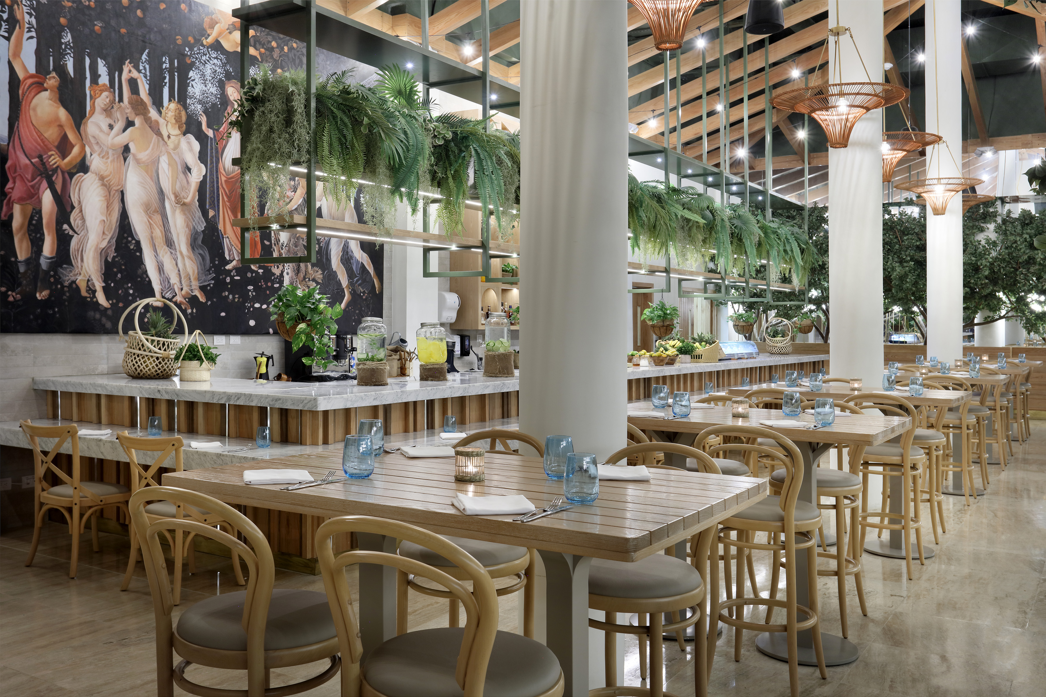 Elegant tropical restaurant interior with wooden tables, greenery, and classical mural.