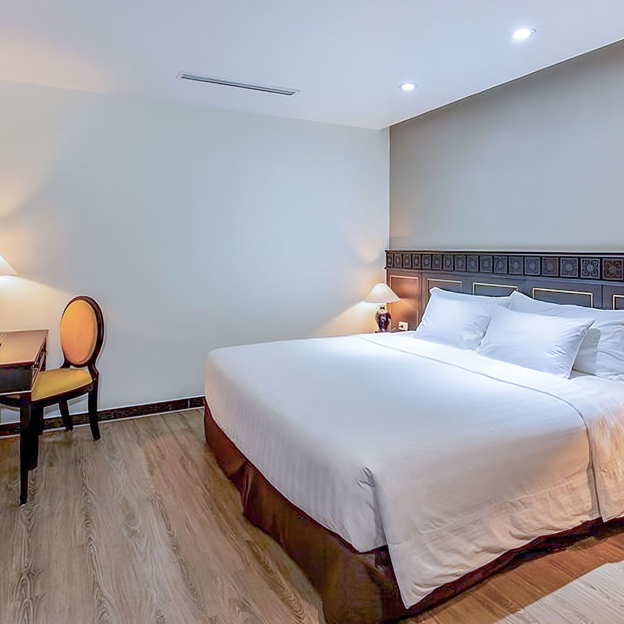 a bed with white sheets and a table and chairs in a room