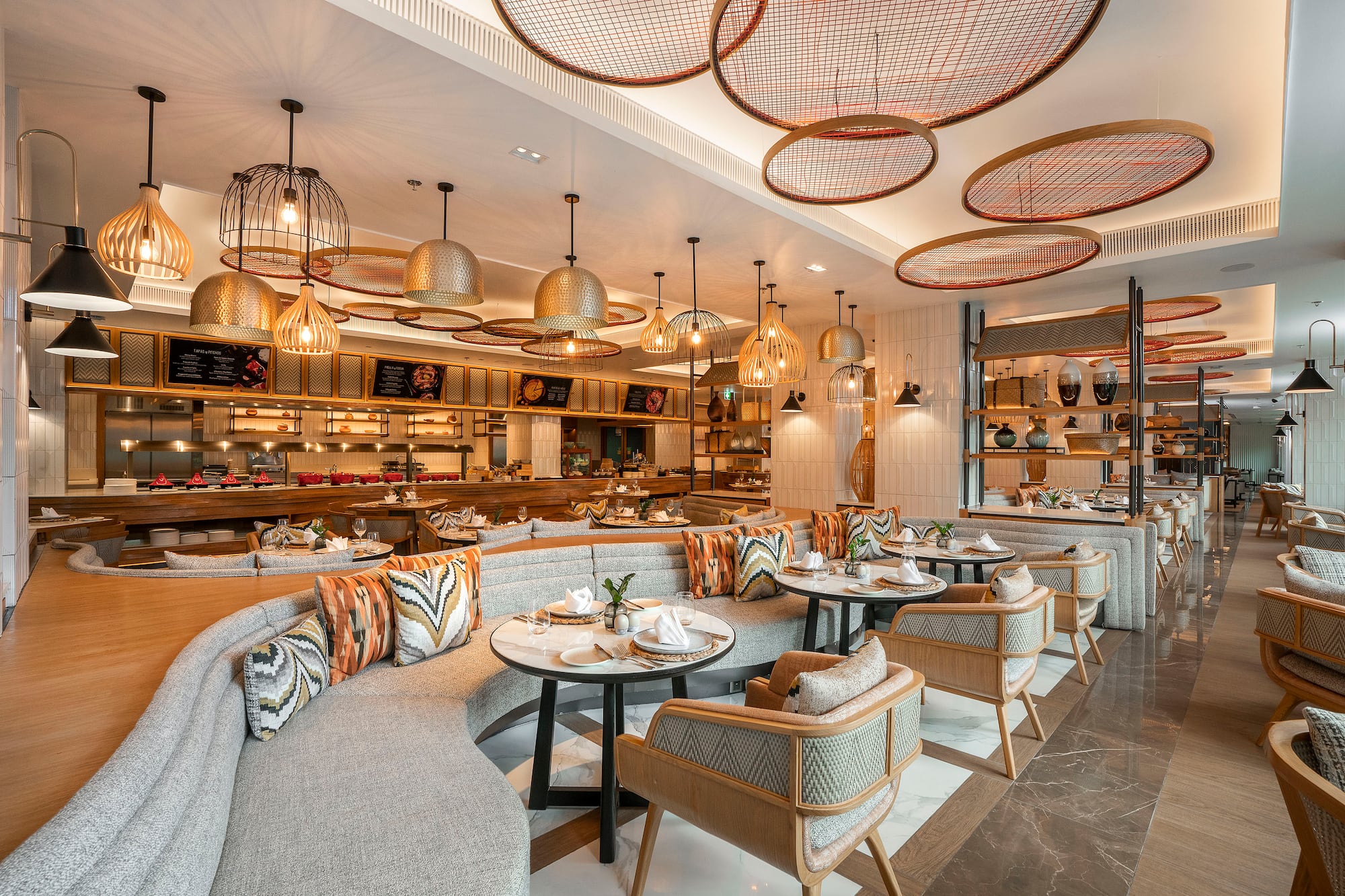 Modern restaurant interior with curved seating, stylish lights, and buffet.