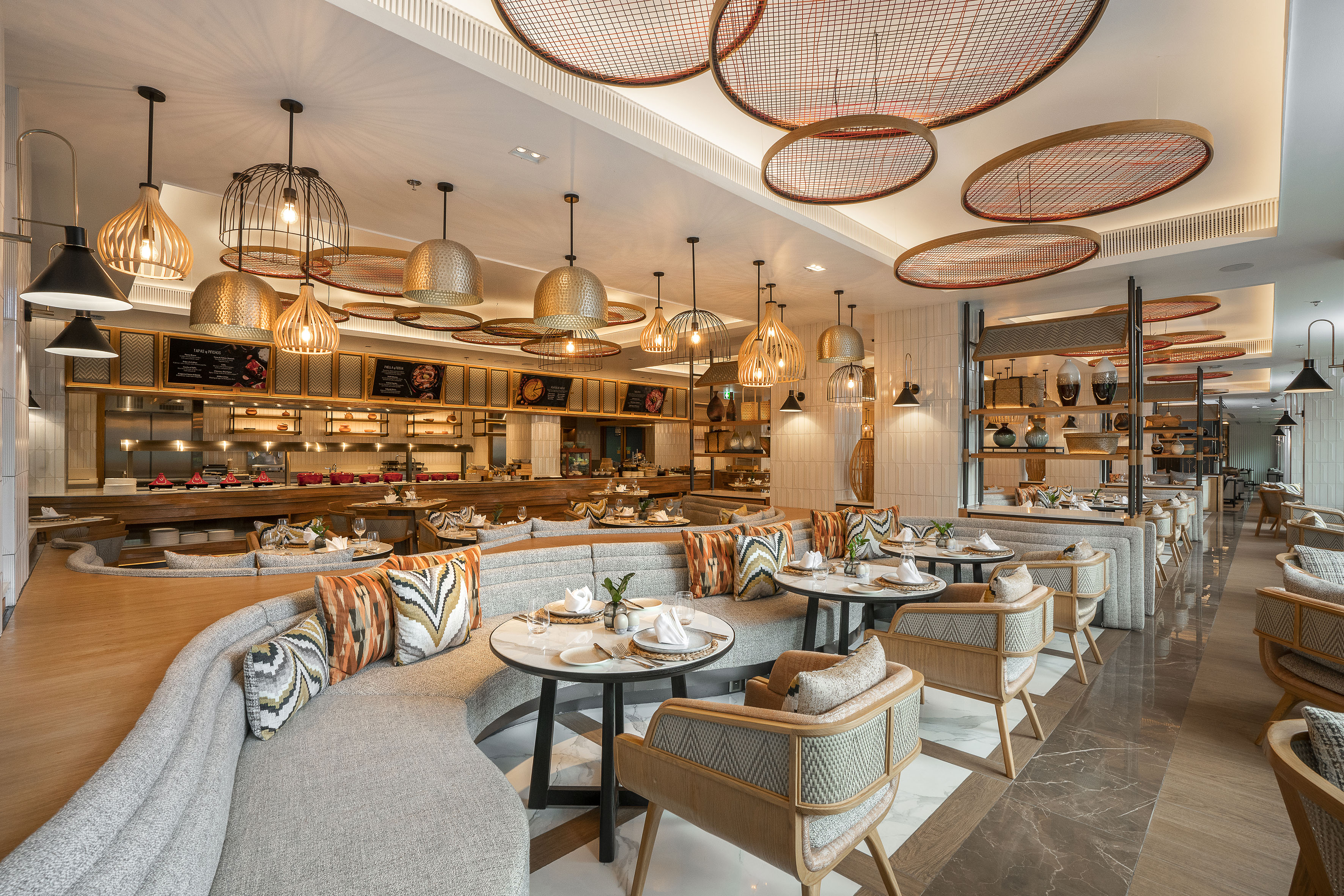 Modern restaurant interior with curved seating, stylish lights, and buffet.