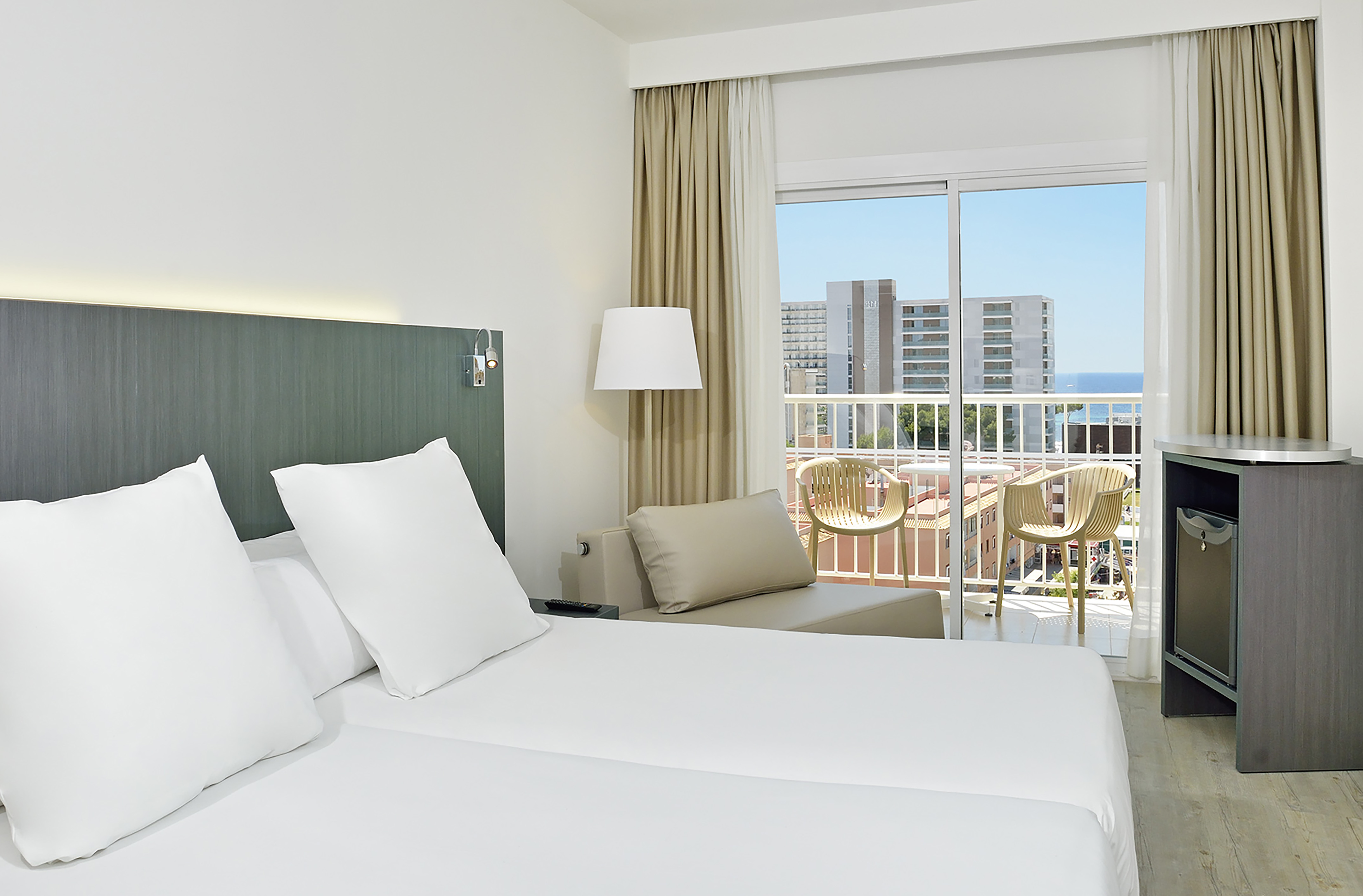 Resort hotel room with balcony, twin beds, and panoramic ocean view.