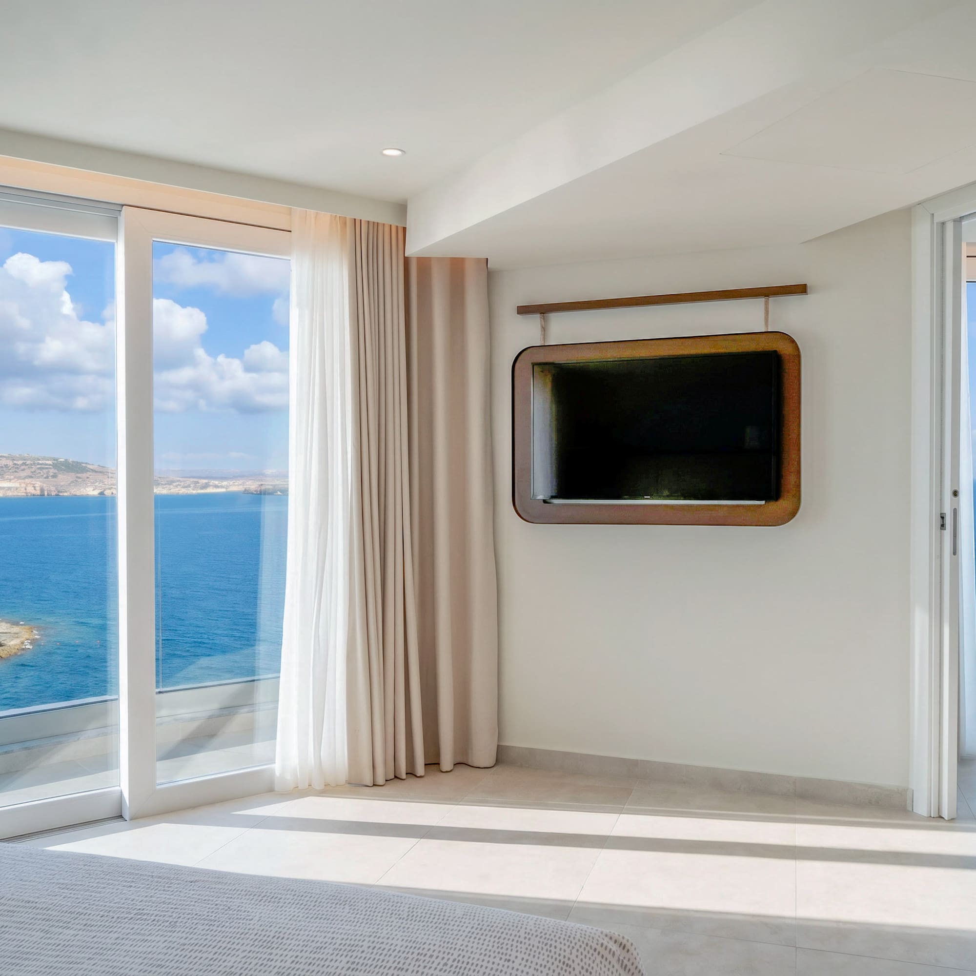 Modern bedroom with expansive ocean view, large windows, and wall-mounted TV.