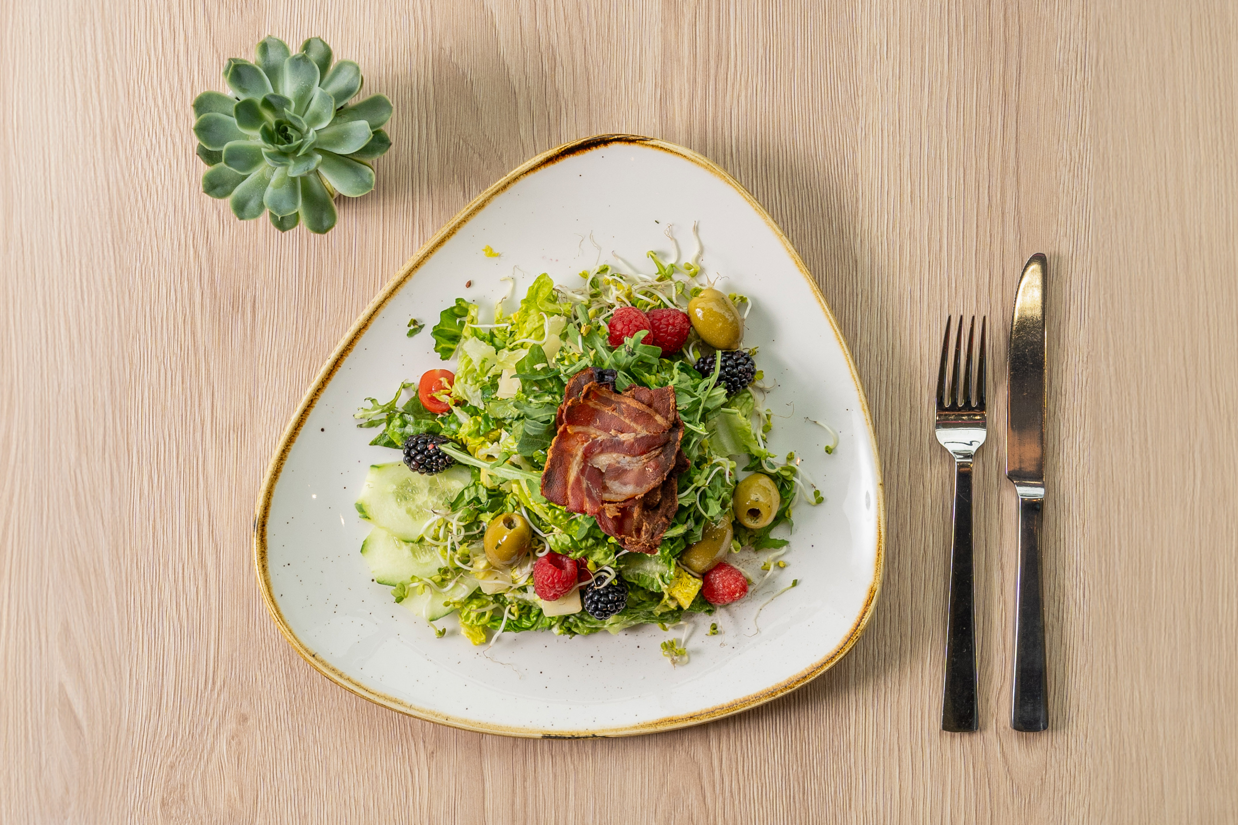 a plate of salad with a fork and knife