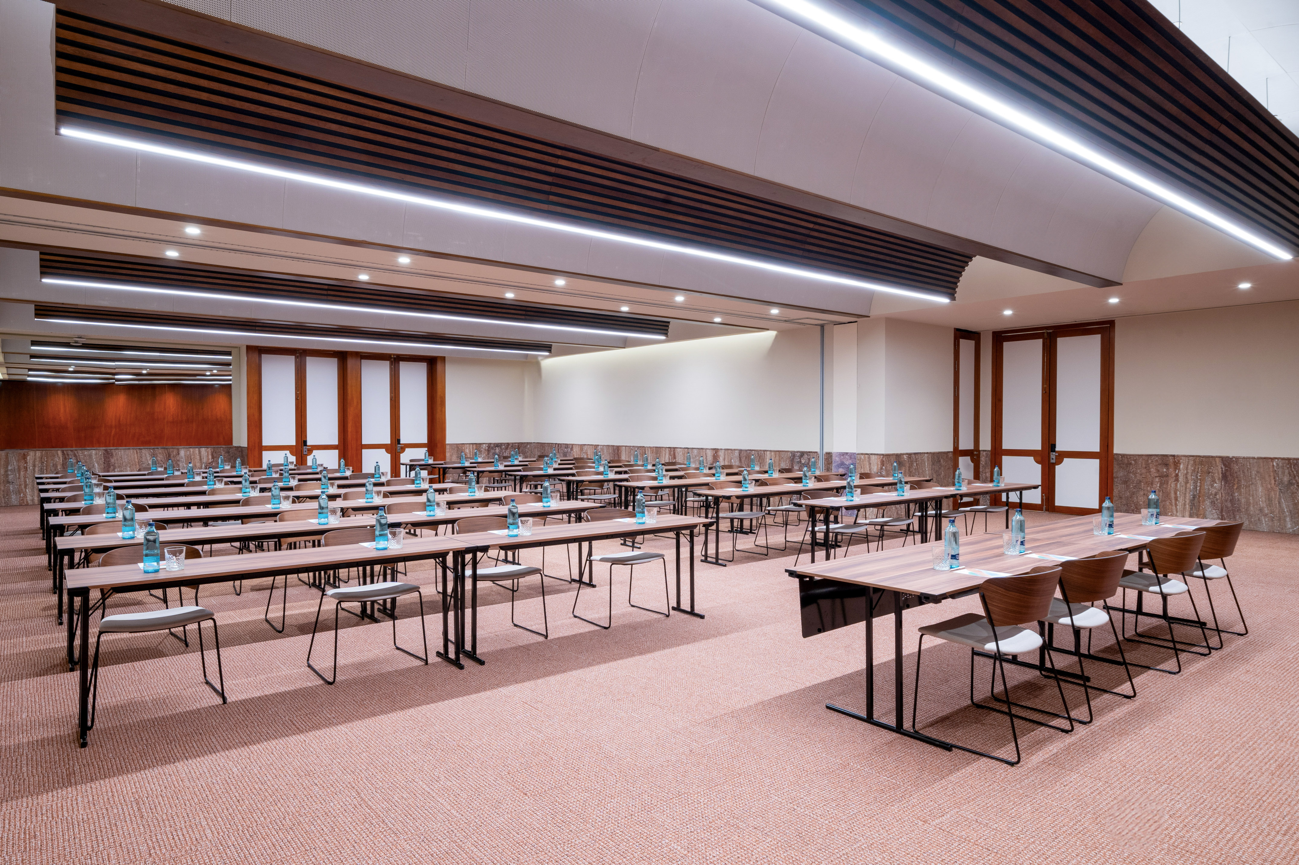 Spacious, modern conference room with tables, chairs, and bottled water.