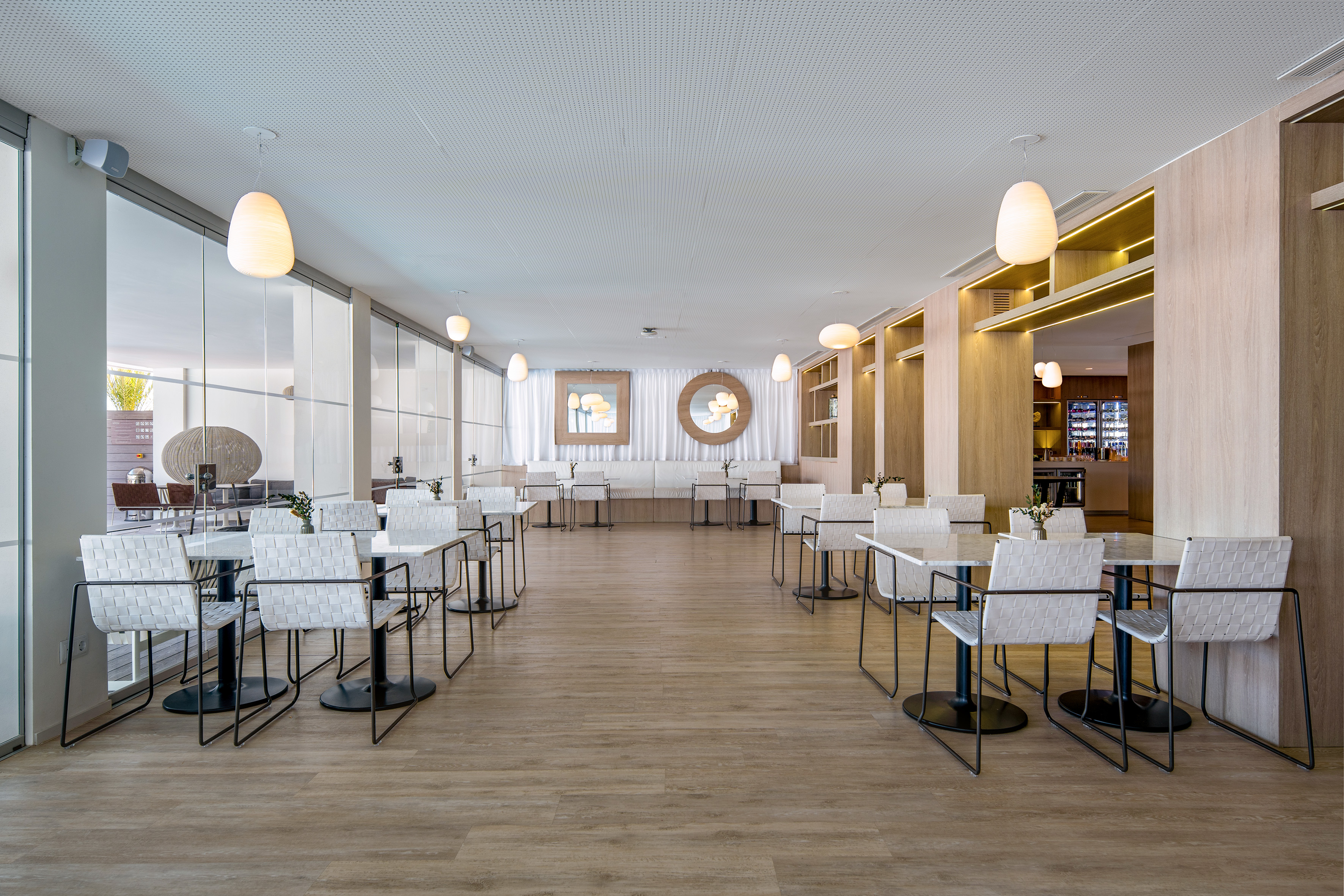 Bright modern restaurant dining area with white chairs, light wood floors.
