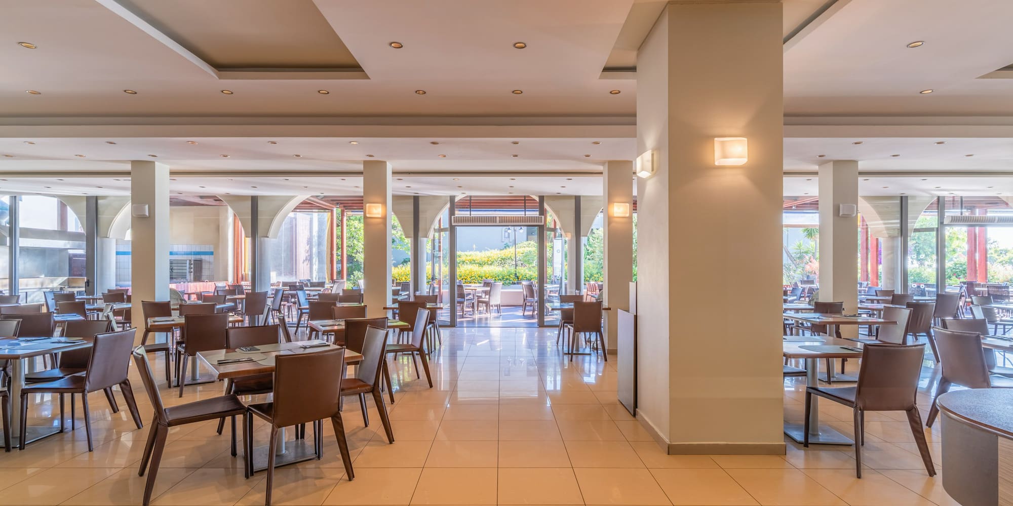 Empty modern restaurant dining area with tiled floor and outdoor view.