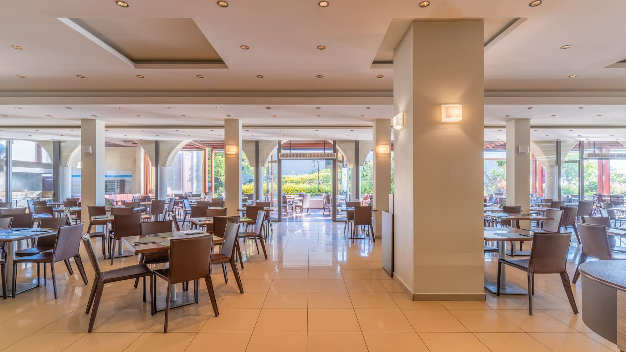 Empty modern restaurant dining area with tiled floor and outdoor view.