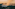 Misty cascades of Iguazu Falls at sunset, enveloped by dense jungle.