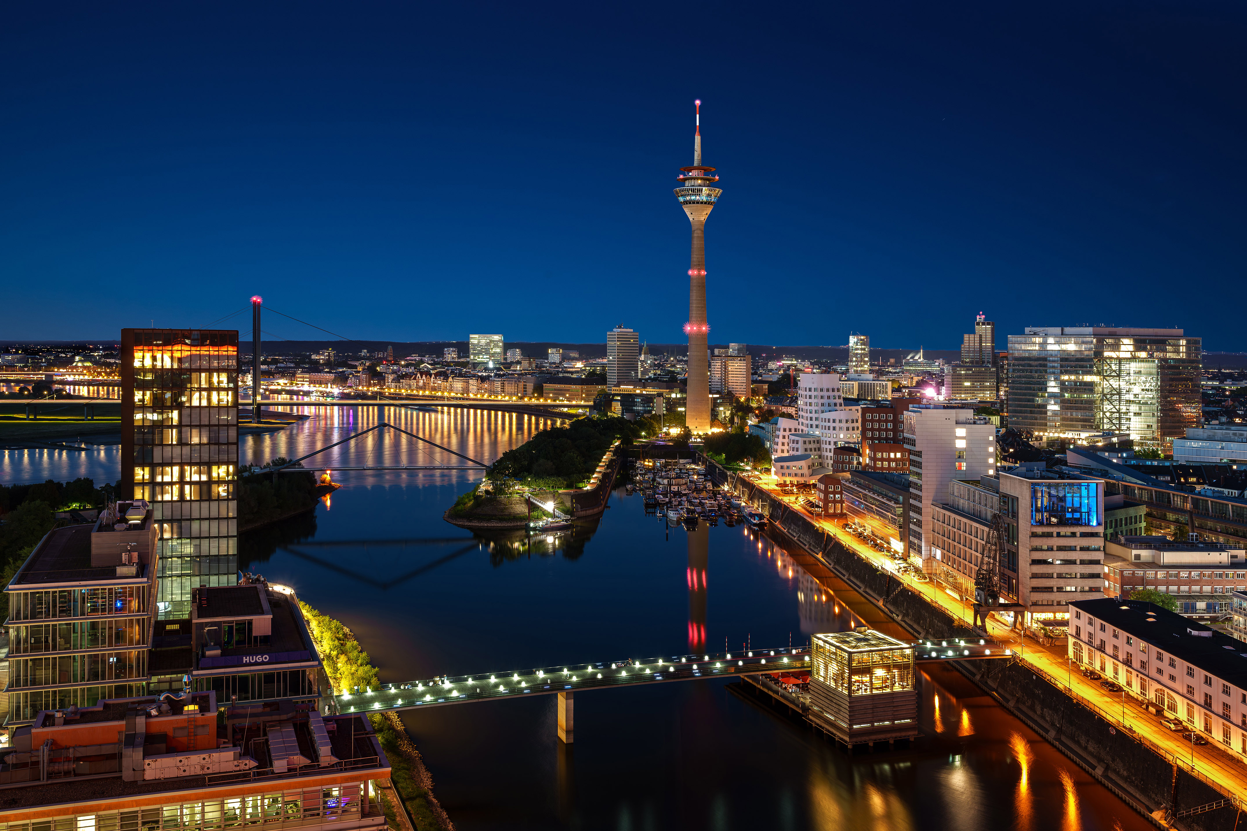 Düsseldorf night view: Rheinturm, Rhine river, bright modern buildings and bridges.