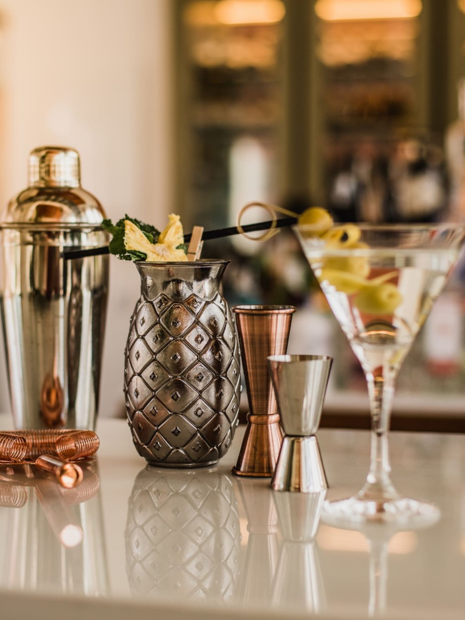 a cocktail shaker and a drink on a bar counter