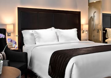 a bed with white sheets and a black and brown headboard