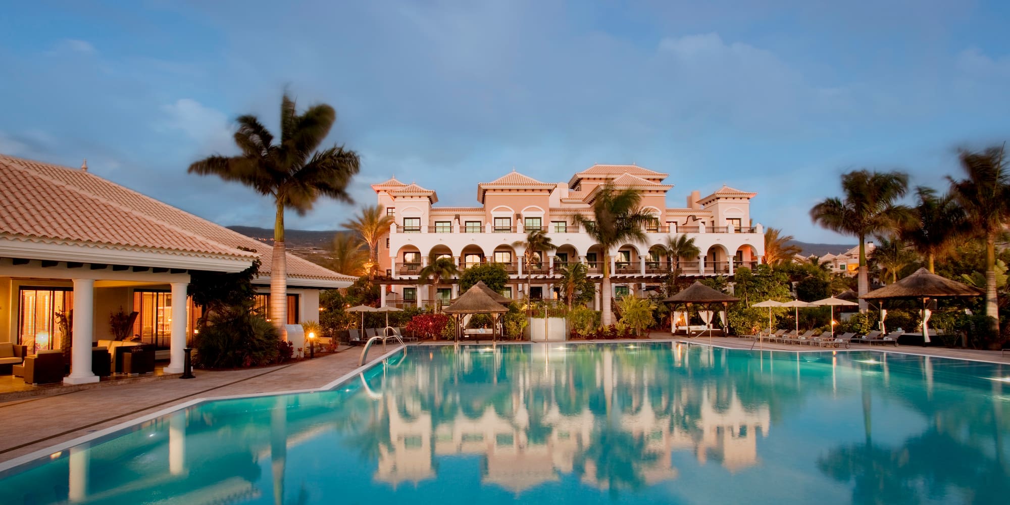 a pool with palm trees and buildings in the background