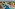 Tropical resort aerial: large pool, palm trees, hotel, ocean view.
