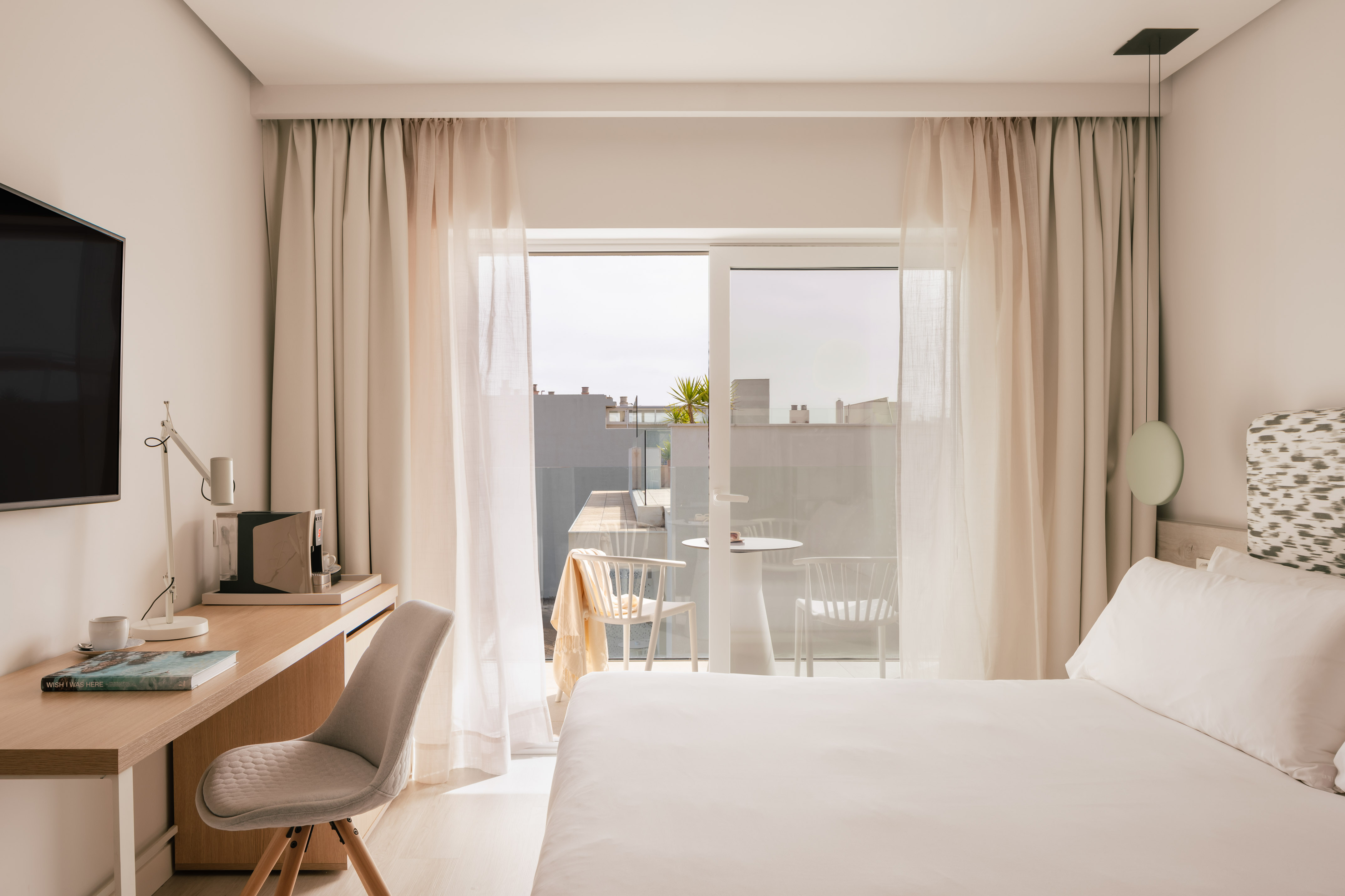 Habitación de hotel moderna con cama, escritorio y balcón con vistas.