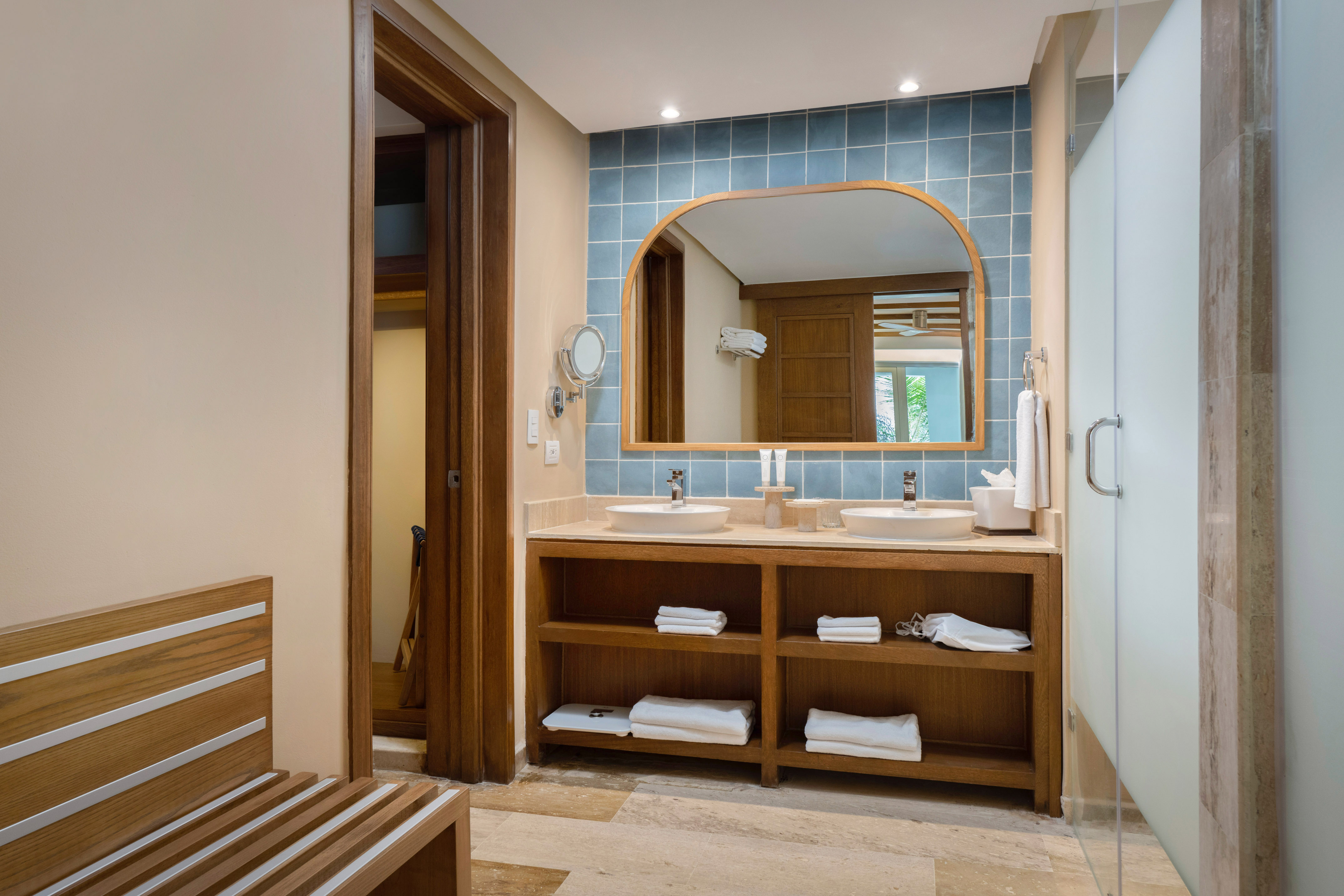 Modern bathroom: double wood vanity, blue tile wall, frosted glass shower.