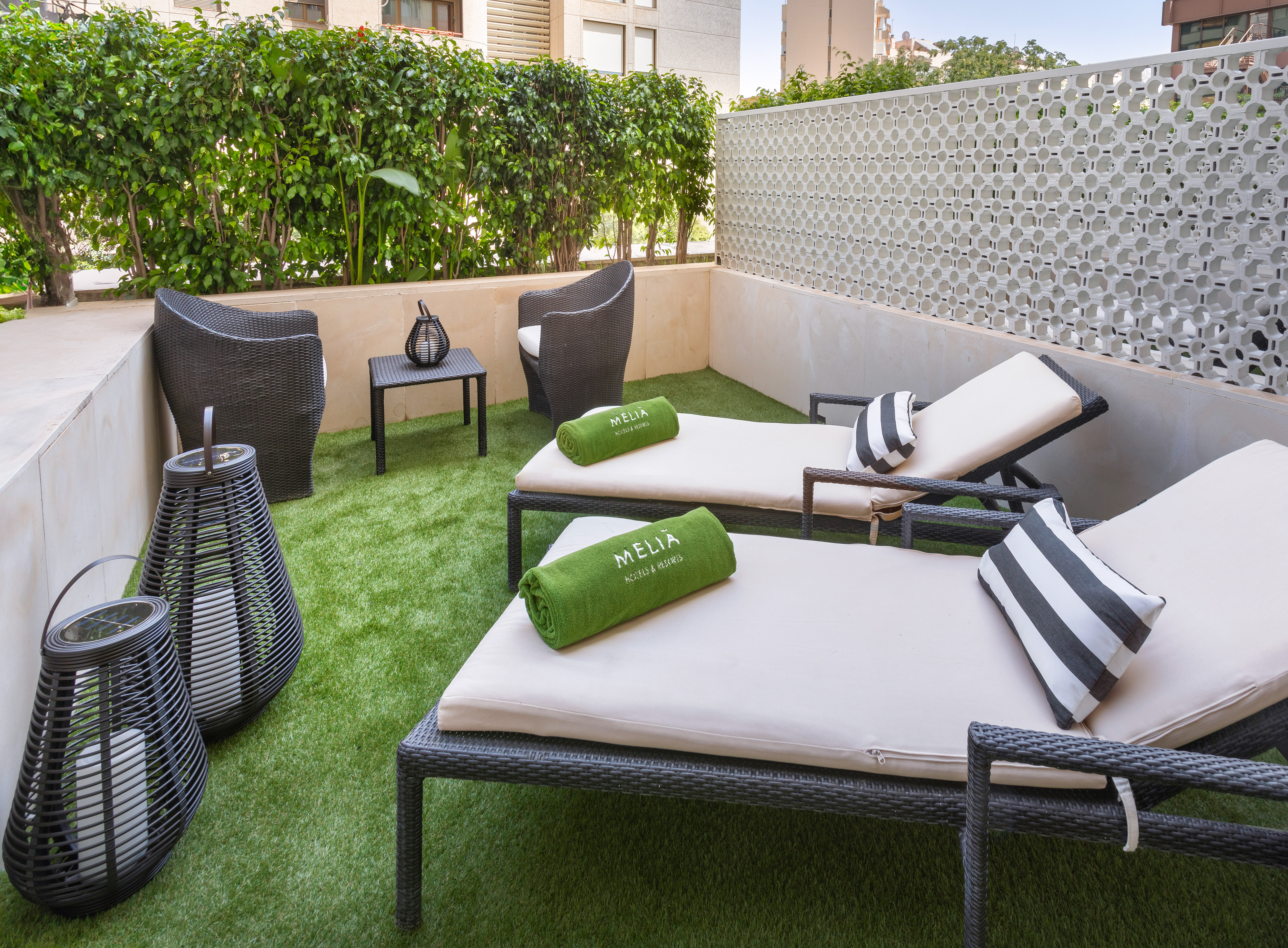 Stylish Melia hotel terrace with sun loungers, green towels, and artificial grass.
