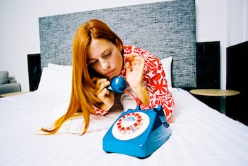 a woman on a bed talking on a blue telephone