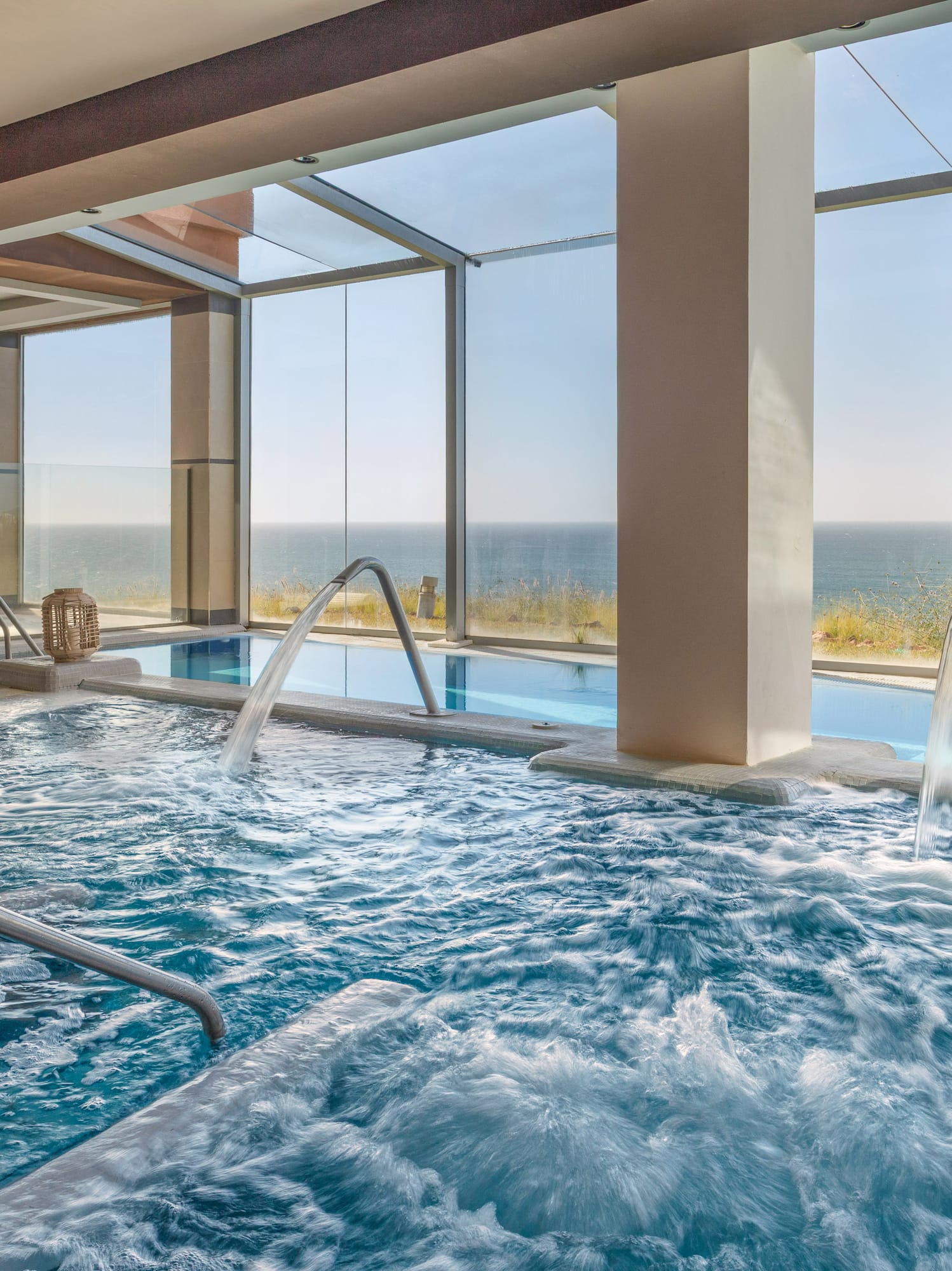 Luxurious indoor spa pool with hydrotherapy jets and panoramic sea view.