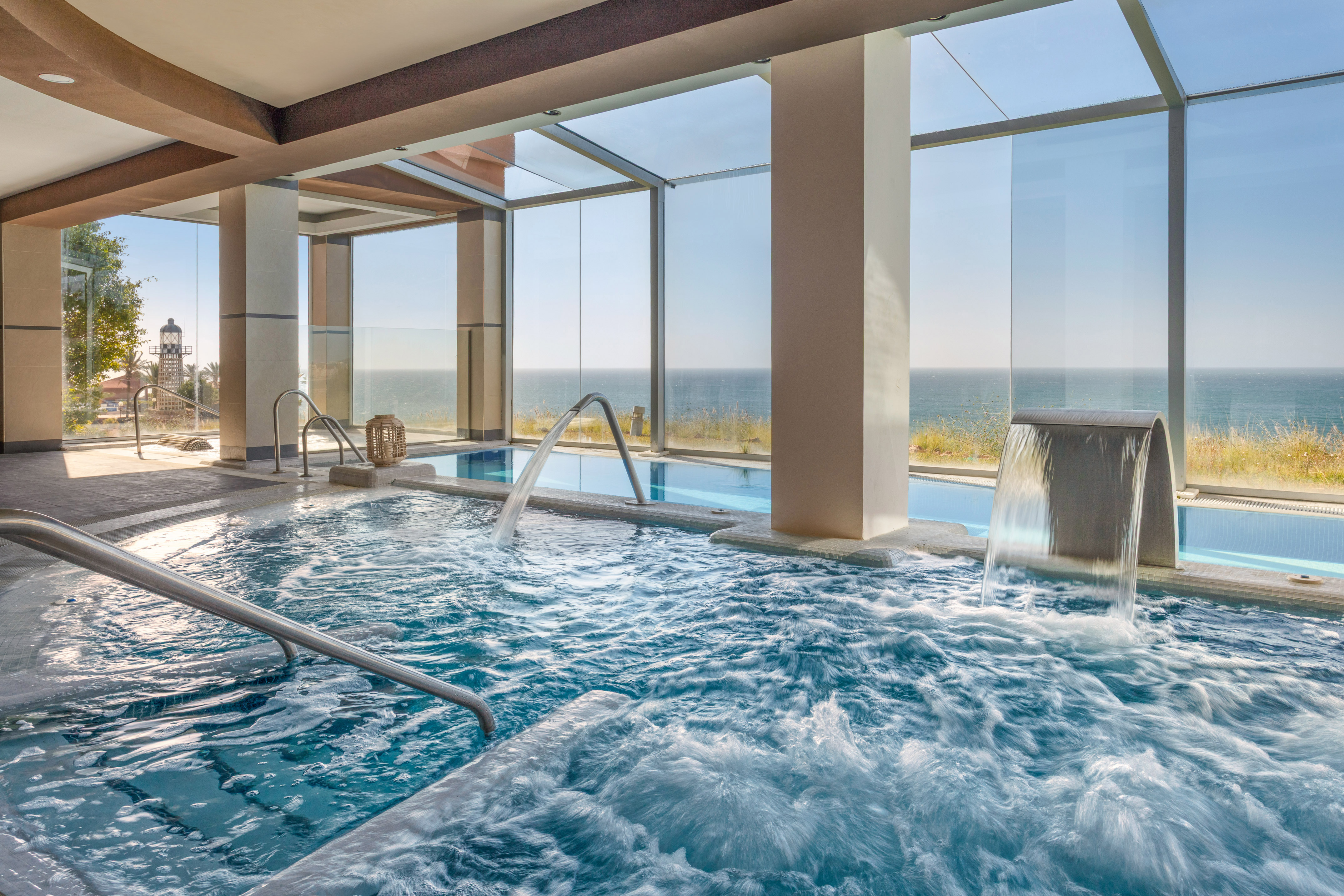 Luxurious indoor spa pool with hydrotherapy jets and panoramic sea view.