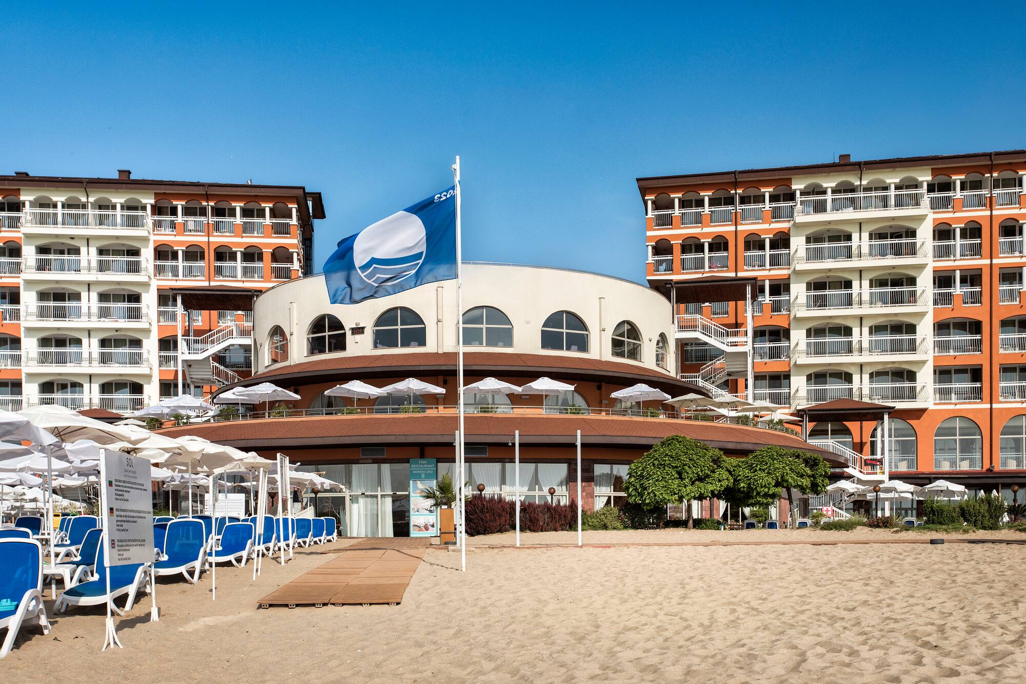 a building with a flag and umbrellas on a beach
