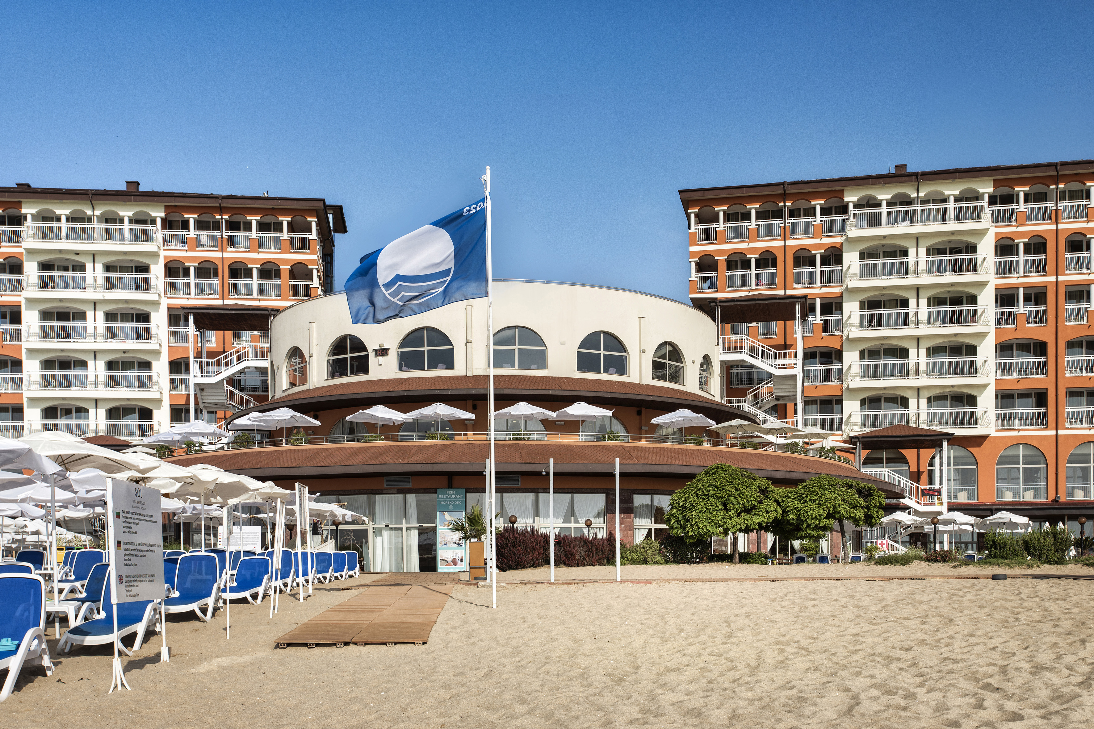 a building with a flag and umbrellas on a beach