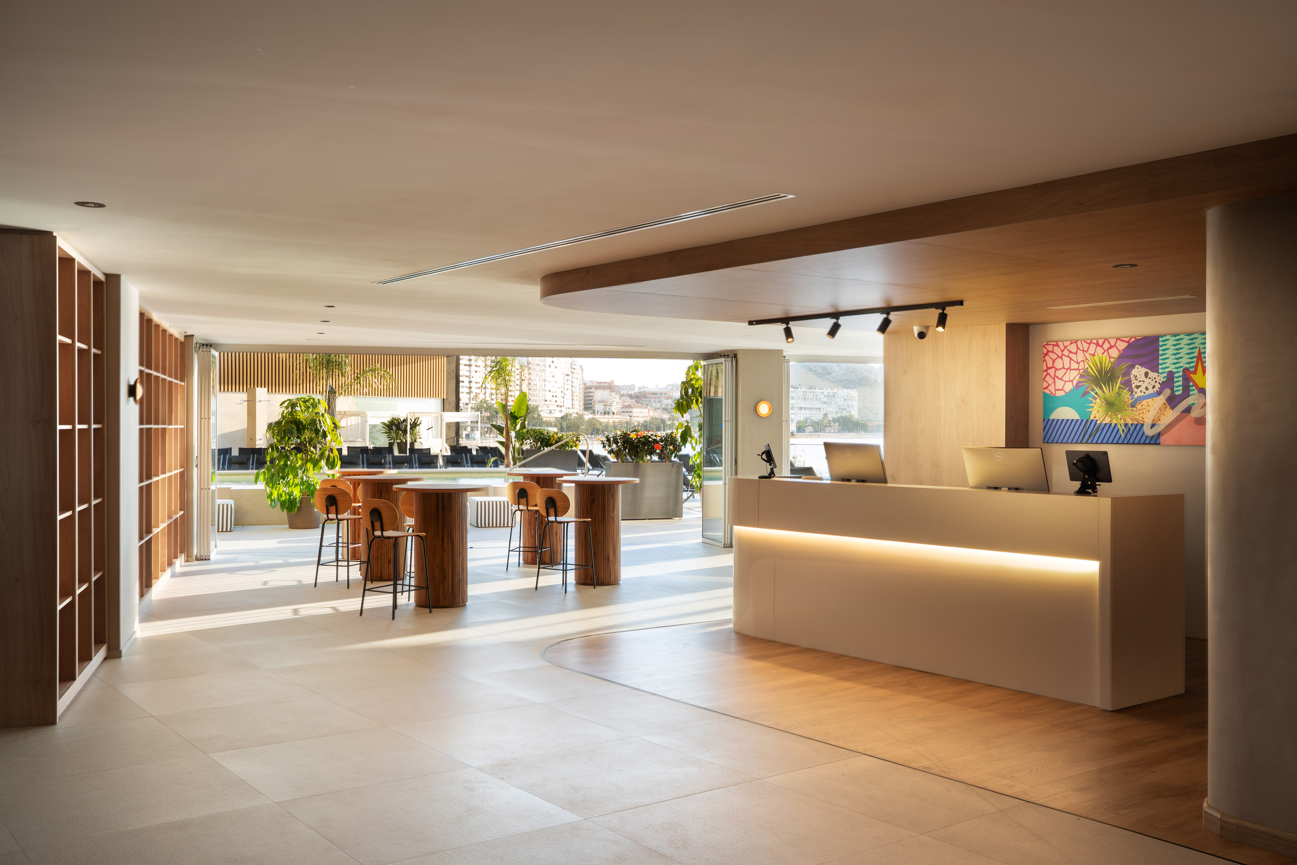 Modern hotel lobby, reception desk, lounge seating, waterfront view.
