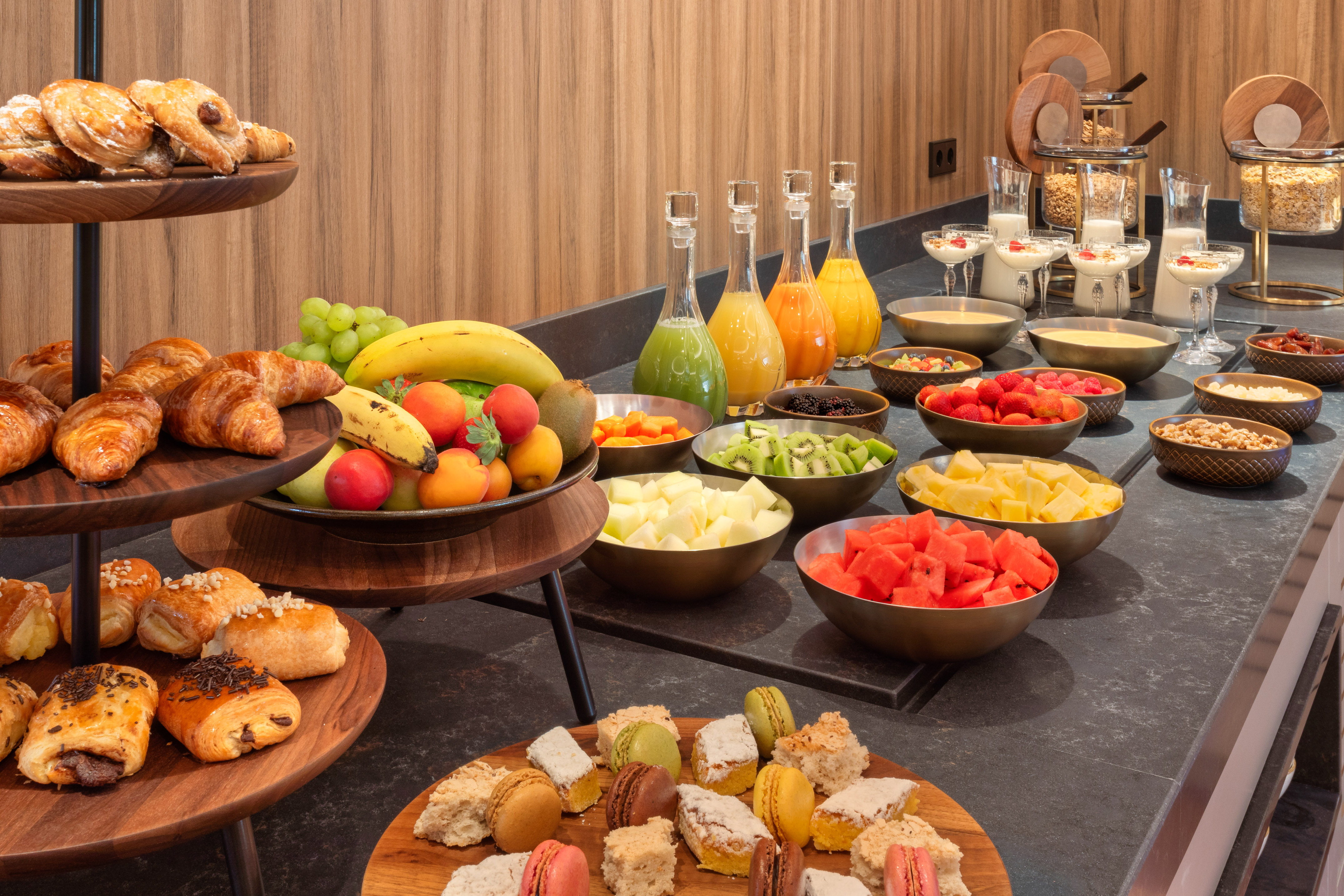 Hotel breakfast buffet with fresh fruits, assorted pastries, juices, and cereals.